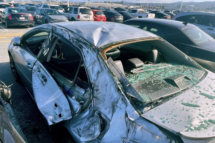 FILE - A damaged car is seen in a airport parking lot after debris from tire which fell from a Boeing 777 landed on it at San Francisco International Airport, March 7, 2024. Cracked windshields on jetliners and engine problems that cause flight delays don't normally attract much attention, but routine and rare problems with passenger planes are attracting an unusual amount of news coverage. (AP Photo/Haven Daley, File)