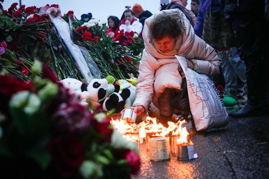 A woman lights candles at the fence next to the Crocus City Hall, on the western edge of Moscow, Russia, Saturday, March 23, 2024. Russia's top state investigative agency says the death toll in the Moscow concert hall attack has risen to over 133. The attack Friday on Crocus City Hall, a sprawling mall and concert venue on Moscow's western edge, also left many wounded and left the building a smoldering ruin. (AP Photo/Alexander Zemlianichenko)