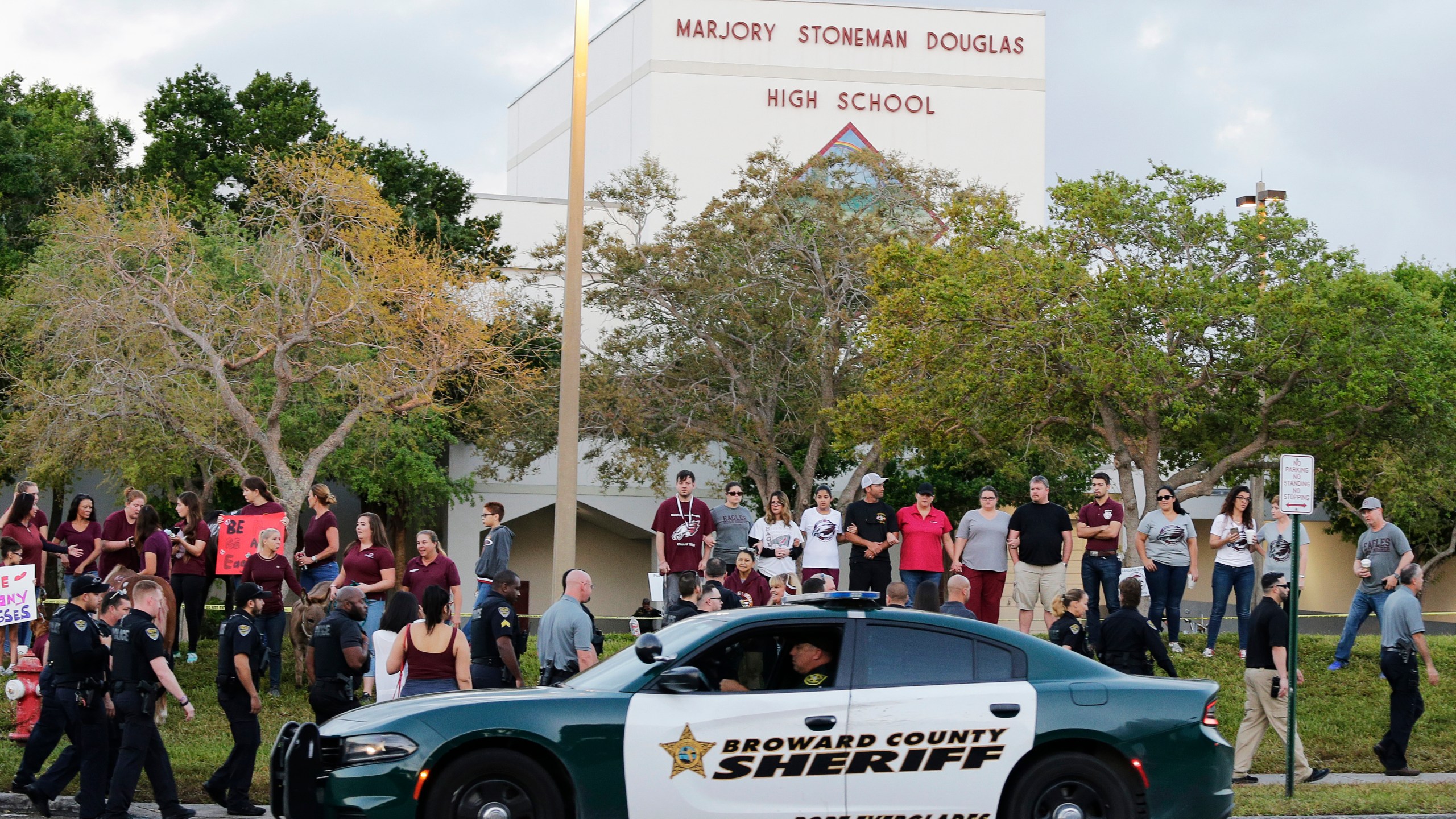 FILE - In this Feb. 28, 2018 photo, a police car drives by Marjory Stoneman Douglas High School in Parkland, Fla., as students returned to class for the first time since a former student opened fire there with an assault weapon. Vice President Kamala Harris will tour on Saturday, March 23, 2024, the blood-stained classroom building where the 2018 Parkland high school massacre happened, accompanied by some victims' family members who are pushing for stricter gun laws and improved school safety. (AP Photo/Terry Renna, File)