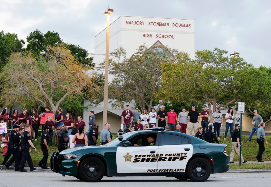 FILE - In this Feb. 28, 2018 photo, a police car drives by Marjory Stoneman Douglas High School in Parkland, Fla., as students returned to class for the first time since a former student opened fire there with an assault weapon. Vice President Kamala Harris will tour on Saturday, March 23, 2024, the blood-stained classroom building where the 2018 Parkland high school massacre happened, accompanied by some victims' family members who are pushing for stricter gun laws and improved school safety. (AP Photo/Terry Renna, File)