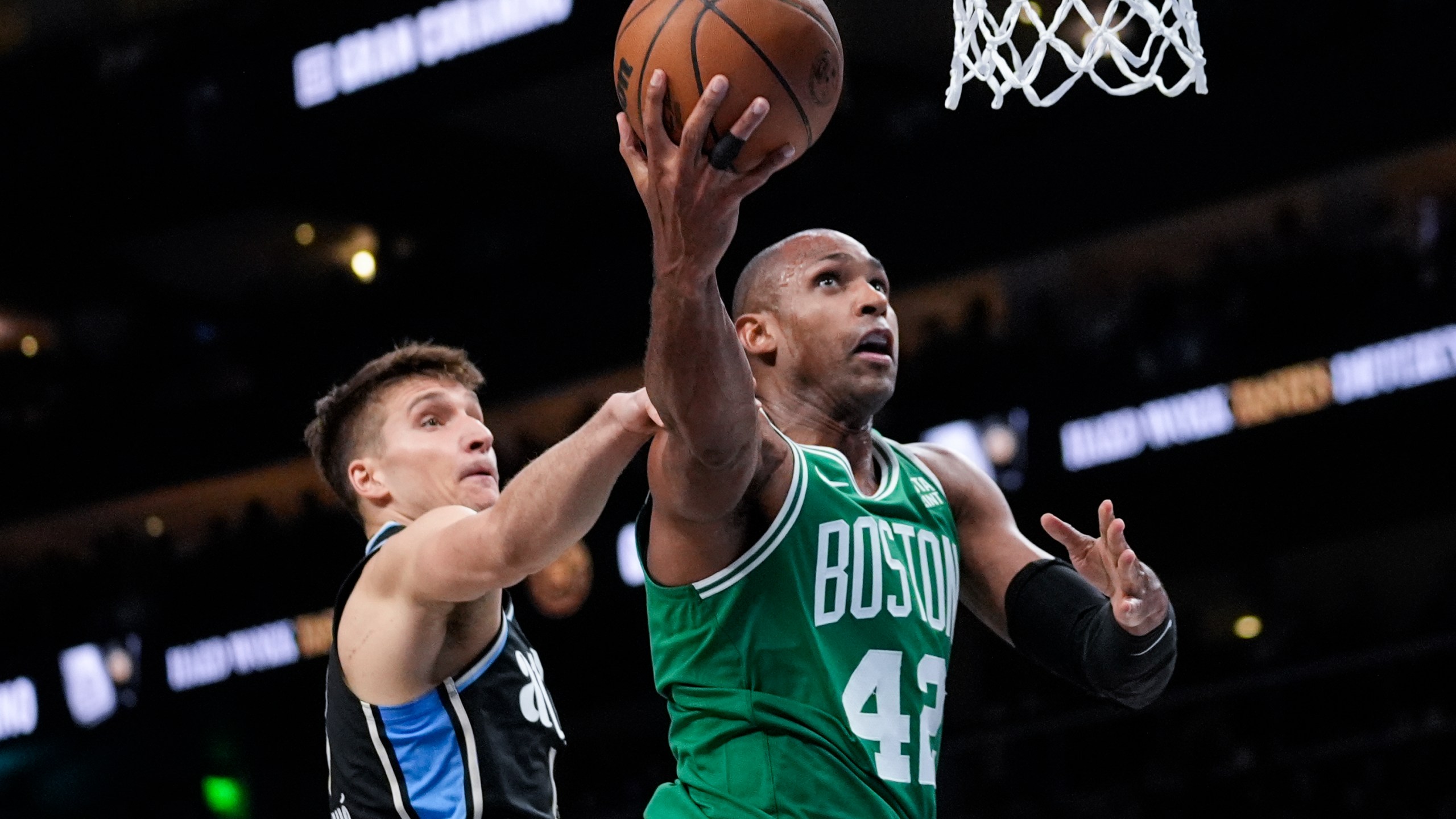 Boston Celtics center Al Horford (42) is fouled by Atlanta Hawks guard Bogdan Bogdanovic (13) as he goes in for a shot during the second half of an NBA basketball game Monday, March 25, 2024, in Atlanta. (AP Photo/John Bazemore)