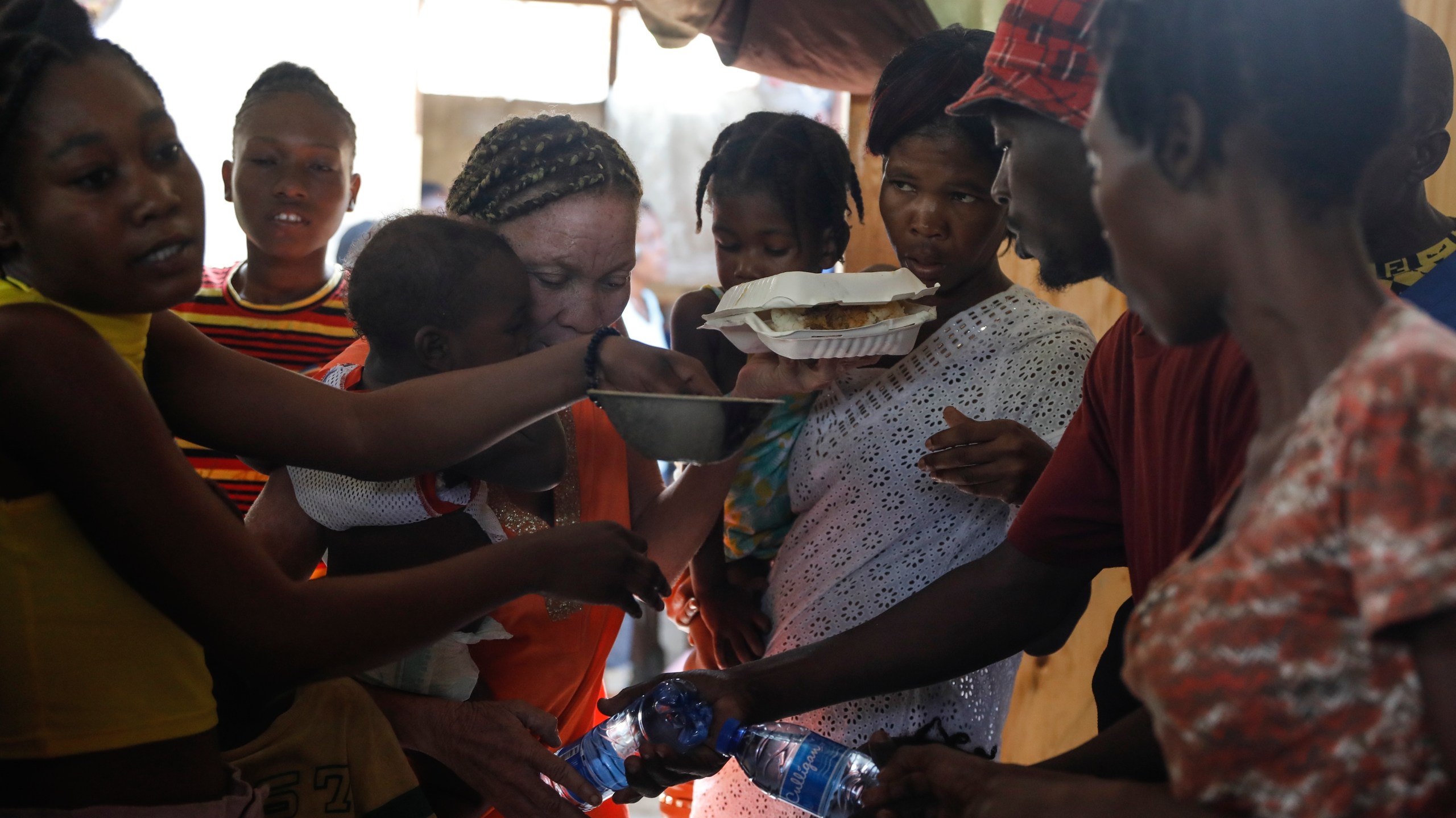 Women scuffle for plates of food for their children at a shelter for families displaced by gang violence, in Port-au-Prince, Haiti, Friday, March 22, 2024. (AP Photo/Odelyn Joseph)