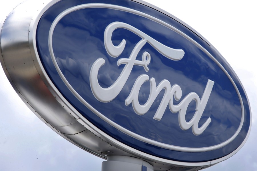 FILE - Clouds are reflected in the Ford sign at a dealership, June 5, 2014, in Wexford, Pa. U.S. auto safety regulators are investigating complaints that more than 540,000 Ford pickup trucks can abruptly downshift to a lower gear and increase the risk of a crash. (AP Photo/Keith Srakocic, File)