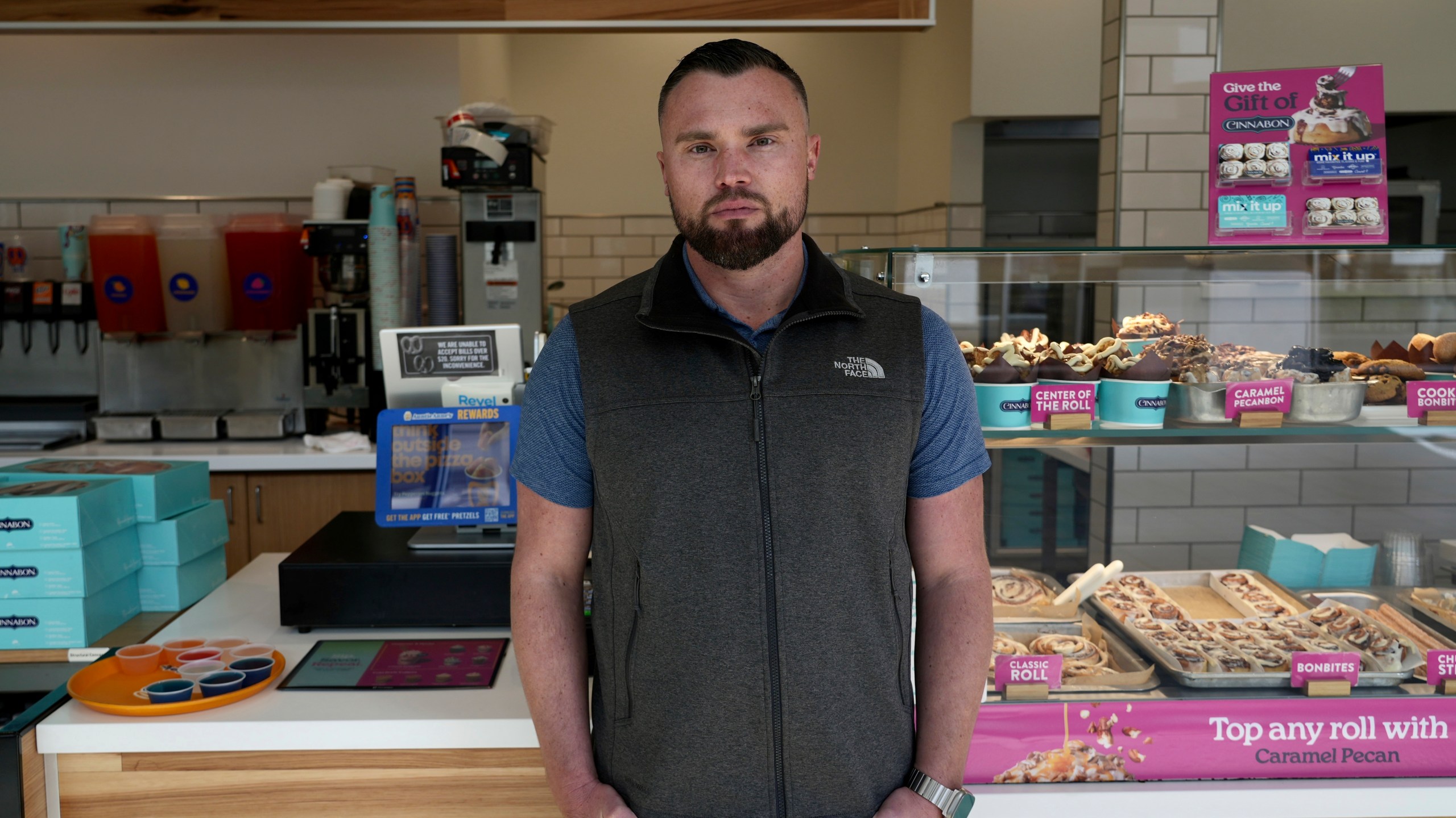 Alex Johnson, who owns 10 Auntie Anne's and Cinnabon stores in the San Francisco Bay area, stands in his store in Livermore, Calif., Thursday, March 28, 2024. He said his stores will have to raise prices to cover the increase in his employees' wages to $20 an hour. (AP Photo/Terry Chea)