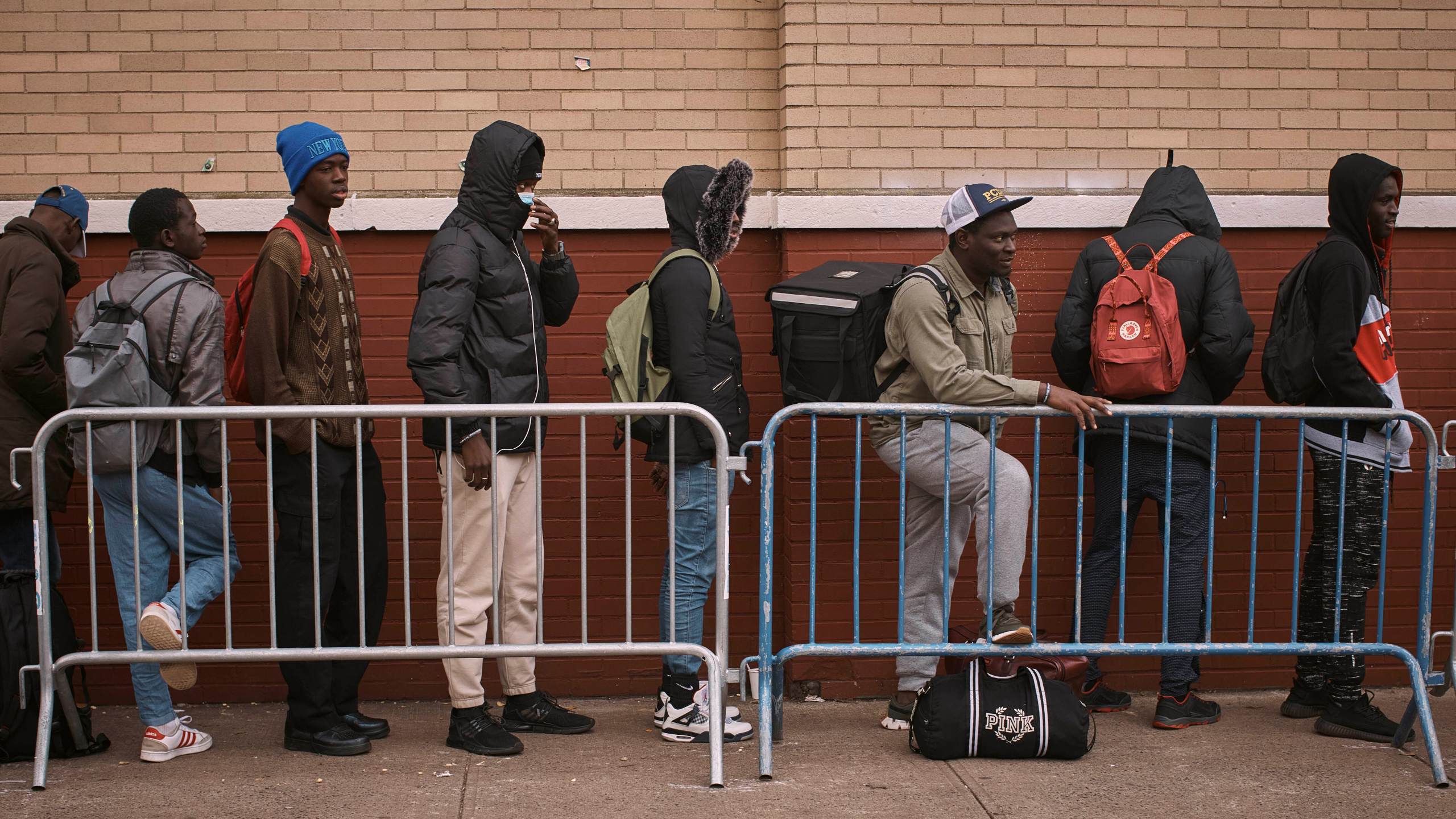 FILE - Migrants queue in the cold as they look for a shelter outside a Migrant Assistance Center at St. Brigid Elementary School on Tuesday, Dec. 5, 2023, in New York. Mayor Eric Adam's office on Tuesday, April 9, 2024, said New York City will end its relationship with a medical services company tasked with housing and caring for an influx of international migrants, following scrutiny over the company's lucrative deal with the city and the quality of its humanitarian services. (AP Photo/Andres Kudacki. File)