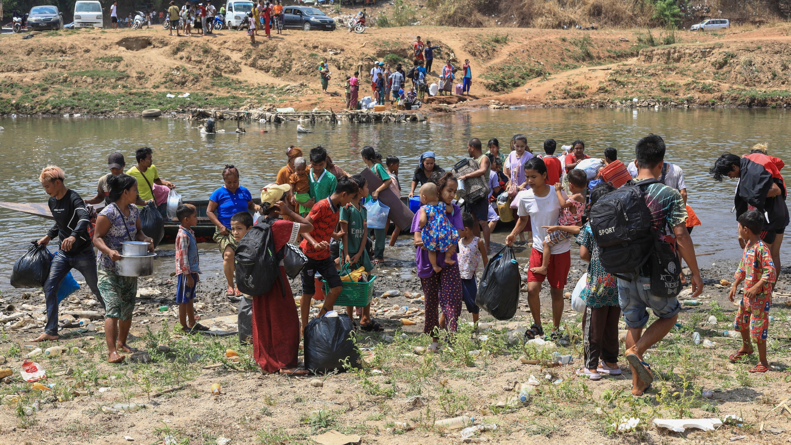 People cross the Moei river as they flee Myawaddy township in Myanmar to Thailand's Mae Sot town in Thailand's Tak province, Saturday, April 20, 2024. About 1,300 people have fled from eastern Myanmar into Thailand, officials said Saturday, as fresh fighting erupted near a border town that has recently been captured by ethnic guerillas. (AP Photo/Warangkana Wanichachewa)