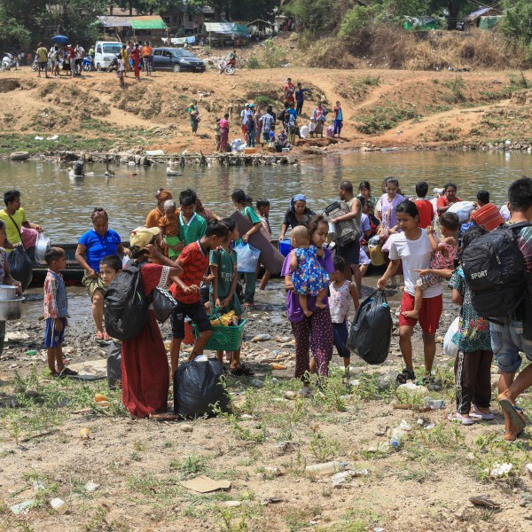 People cross the Moei river as they flee Myawaddy township in Myanmar to Thailand's Mae Sot town in Thailand's Tak province, Saturday, April 20, 2024. About 1,300 people have fled from eastern Myanmar into Thailand, officials said Saturday, as fresh fighting erupted near a border town that has recently been captured by ethnic guerillas. (AP Photo/Warangkana Wanichachewa)