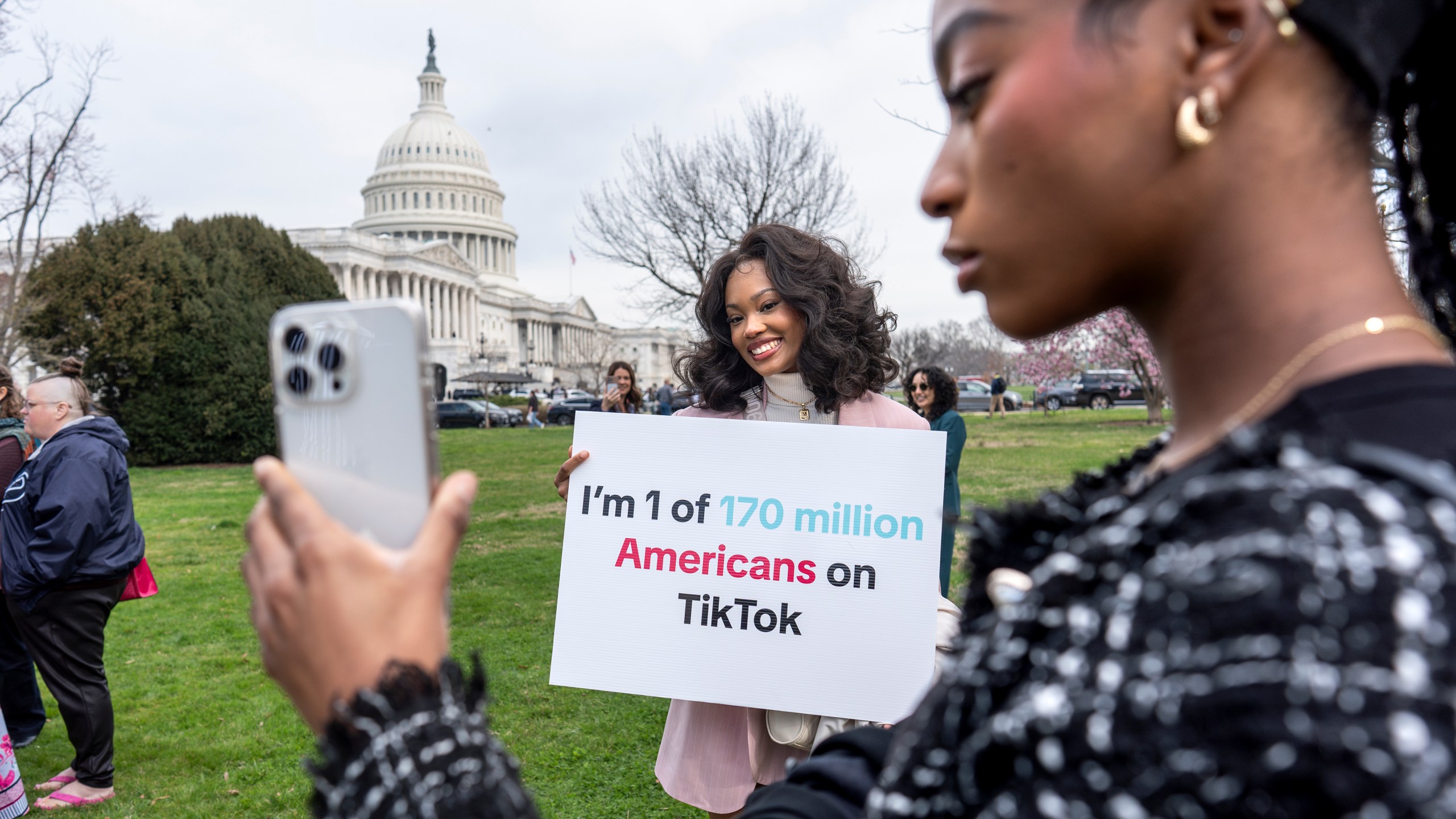 FILE - Devotees of TikTok, Mona Swain, center, and her sister, Rachel Swain, right, both of Atlanta, pose with a sign at the Capitol in Washington, March 13, 2024. TikTok's extensive lobbying campaign is the latest tech industry push since the House passed legislation that would ban the popular app if its China-based owner doesn't sell its stake. TikTok has been urging its users to call their representatives. (AP Photo/J. Scott Applewhite, File)