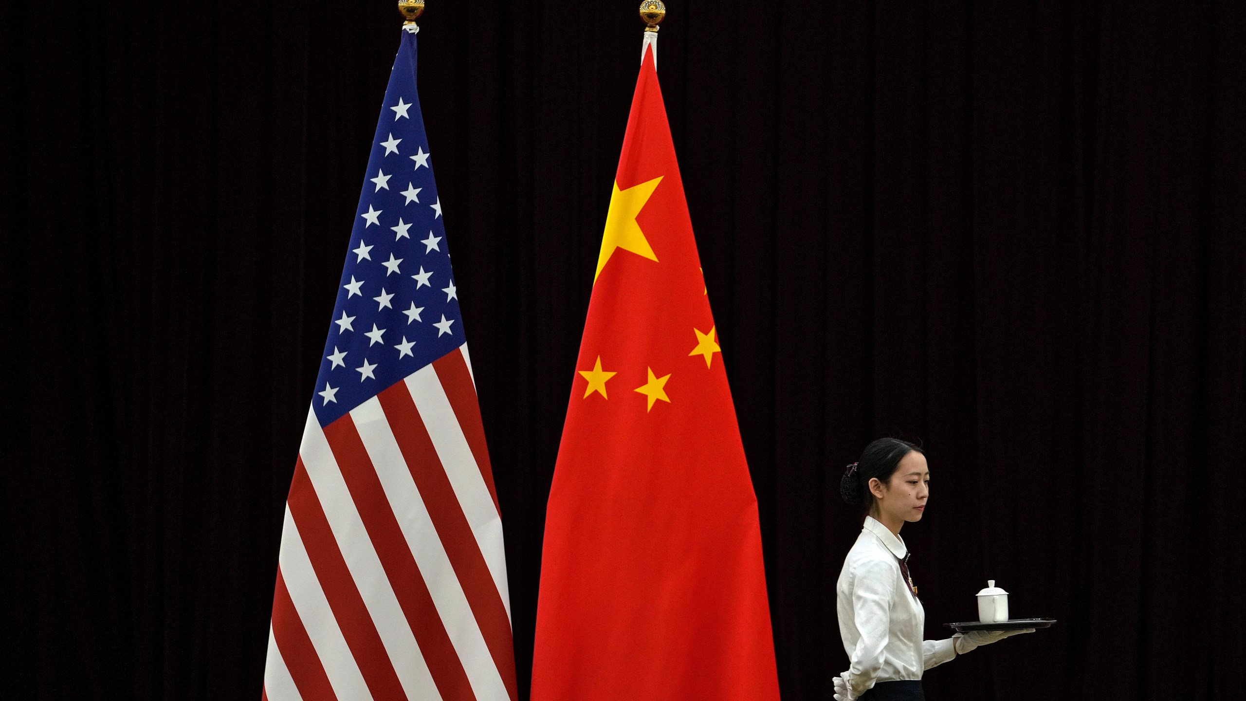 FILE - A hostess walks by the national flags of the United States and China ahead of the bilateral meeting between U.S. Treasury Secretary Janet Yellen and Chinese Vice Premier He Lifeng, at the Guangdong Zhudao Guest House in southern China's Guangdong province, April 6, 2024. Simmering tensions between Beijing and Washington remain the top worry for U.S. companies operating in China, according to a report by the American Chamber of Commerce in China released Tuesday, April 23, 2024. (AP Photo/Andy Wong, Pool, File)