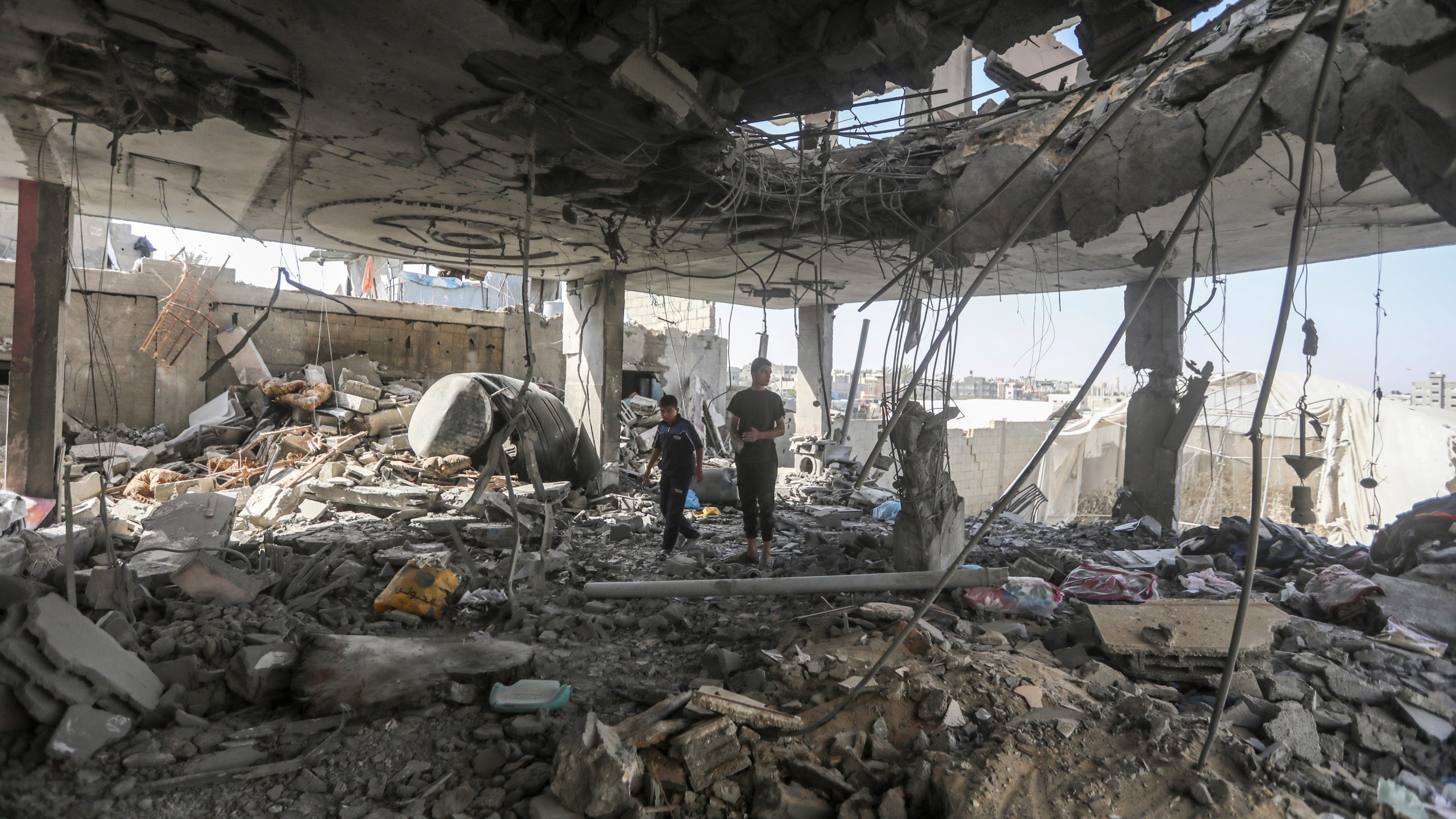 Palestinians stand in the ruins of the Chahine family home, after an overnight Israeli strike that killed at least two adults and five boys and girls under the age of 16 in Rafah, southern Gaza Strip, Friday, May 3, 2024. An Israeli strike on the city of Rafah on the southern edge of the Gaza Strip killed several people, including children, hospital officials said Friday. (AP Photo/Ismael Abu Dayyah)