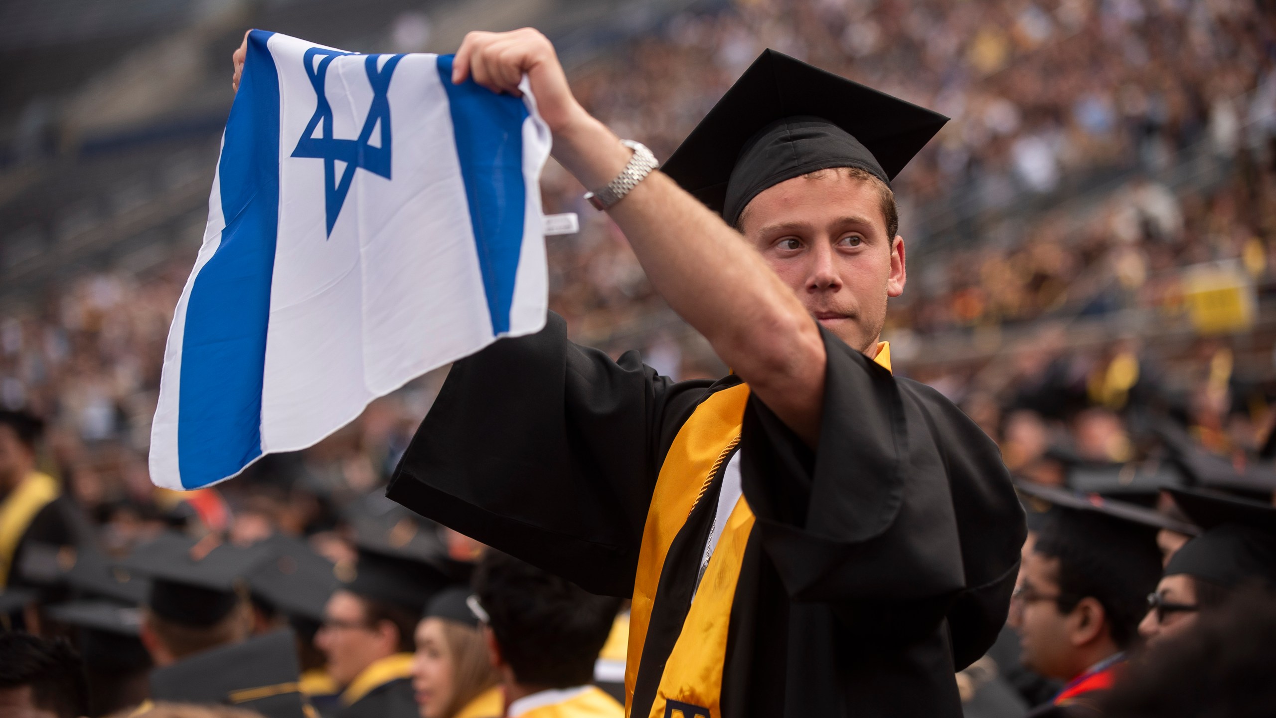 Graduates sporting Israeli flags and pins shout at Pro-Palestinian protesters as they demonstrate during the University of Michigan's Spring 2024 Commencement Ceremony at Michigan Stadium in Ann Arbor, Mich., on Saturday, May 4, 2024. (Katy Kildee/Detroit News via AP)