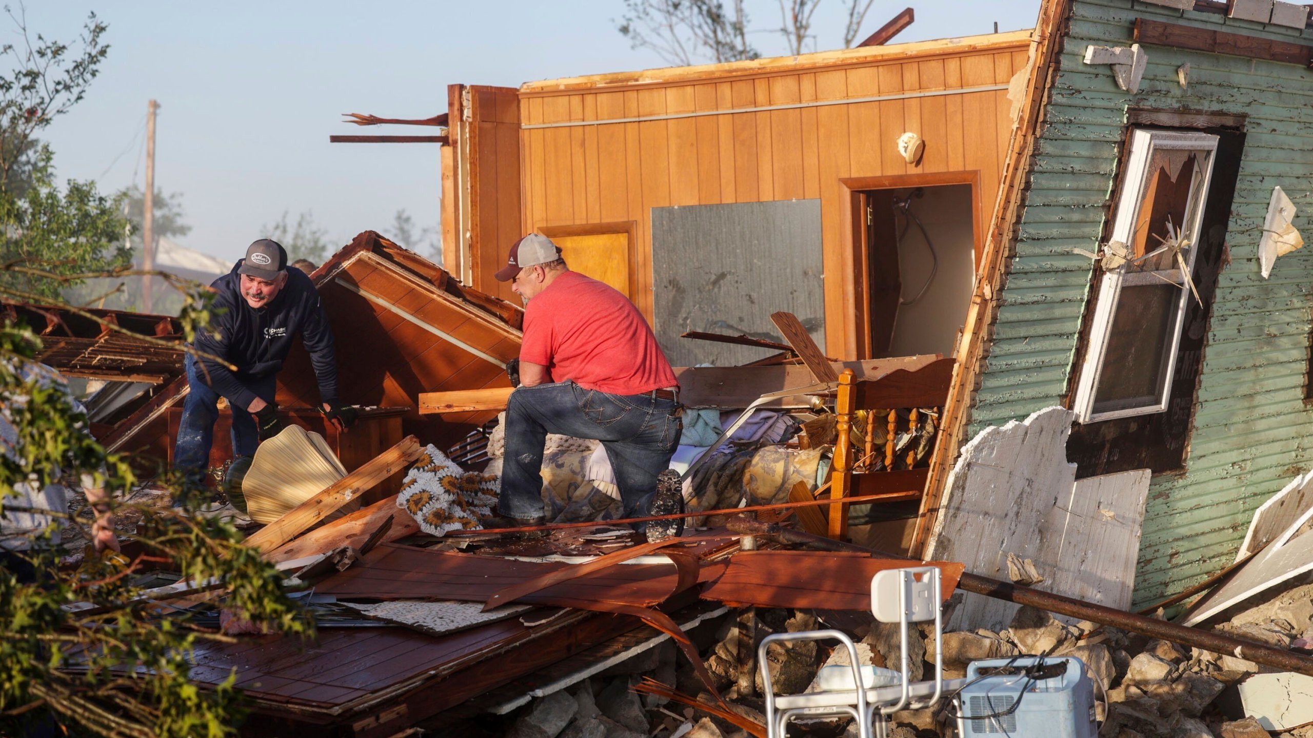 Carl Kelley and Jon Reynolds search through Kelley's mother's home after it was damaged by a severe storm, Tuesday, May 7, 2024, in Barnsdall, Okla. A tornado destroyed homes, forced the evacuation of a nursing home and toppled trees and power lines when it roared through the small Oklahoma town. (Mike Simons/Tulsa World via AP)