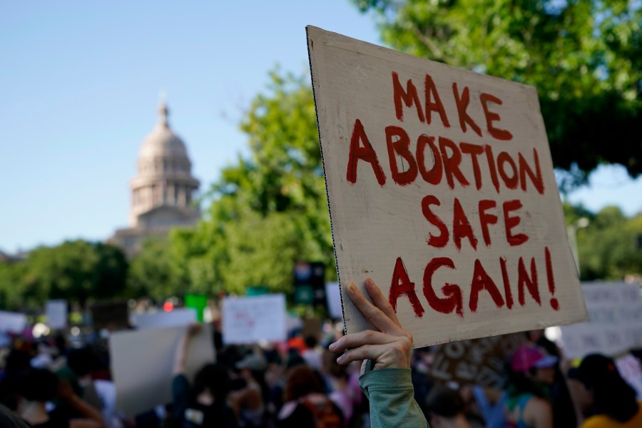 A protester holds a sign saying, "Make abortion safe again."