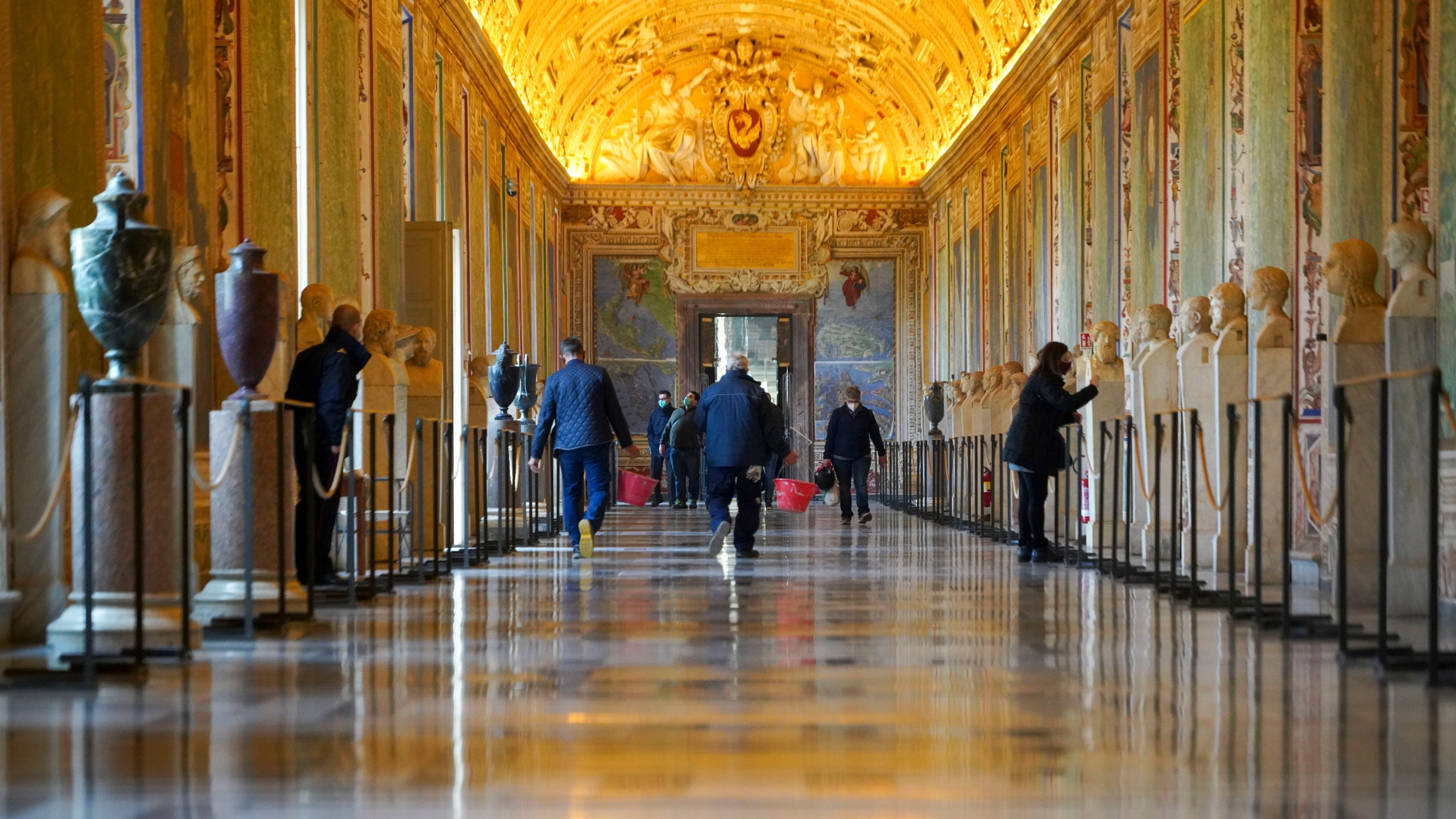 FILE - Museums employees walk down an aisle of the Vatican Museums as they prepare to open the museum, at the Vatican, Monday, Feb. 1, 2021. Forty-nine employees of the Vatican Museums have filed a class-action complaint with the Vatican administration demanding better seniority, leave and overtime benefits in an unusual, public challenge to Pope Francis’ governance. The complaint, dated April 23, 2024, was made public the weekend of May 10, 2024, in Italian newspapers. (AP Photo/Andrew Medichini, File)