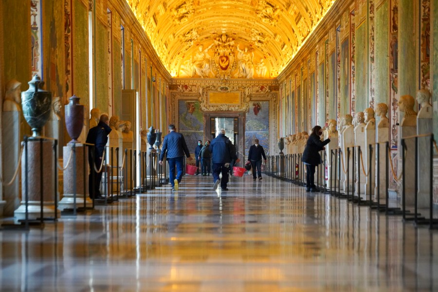 FILE - Museums employees walk down an aisle of the Vatican Museums as they prepare to open the museum, at the Vatican, Monday, Feb. 1, 2021. Forty-nine employees of the Vatican Museums have filed a class-action complaint with the Vatican administration demanding better seniority, leave and overtime benefits in an unusual, public challenge to Pope Francis’ governance. The complaint, dated April 23, 2024, was made public the weekend of May 10, 2024, in Italian newspapers. (AP Photo/Andrew Medichini, File)