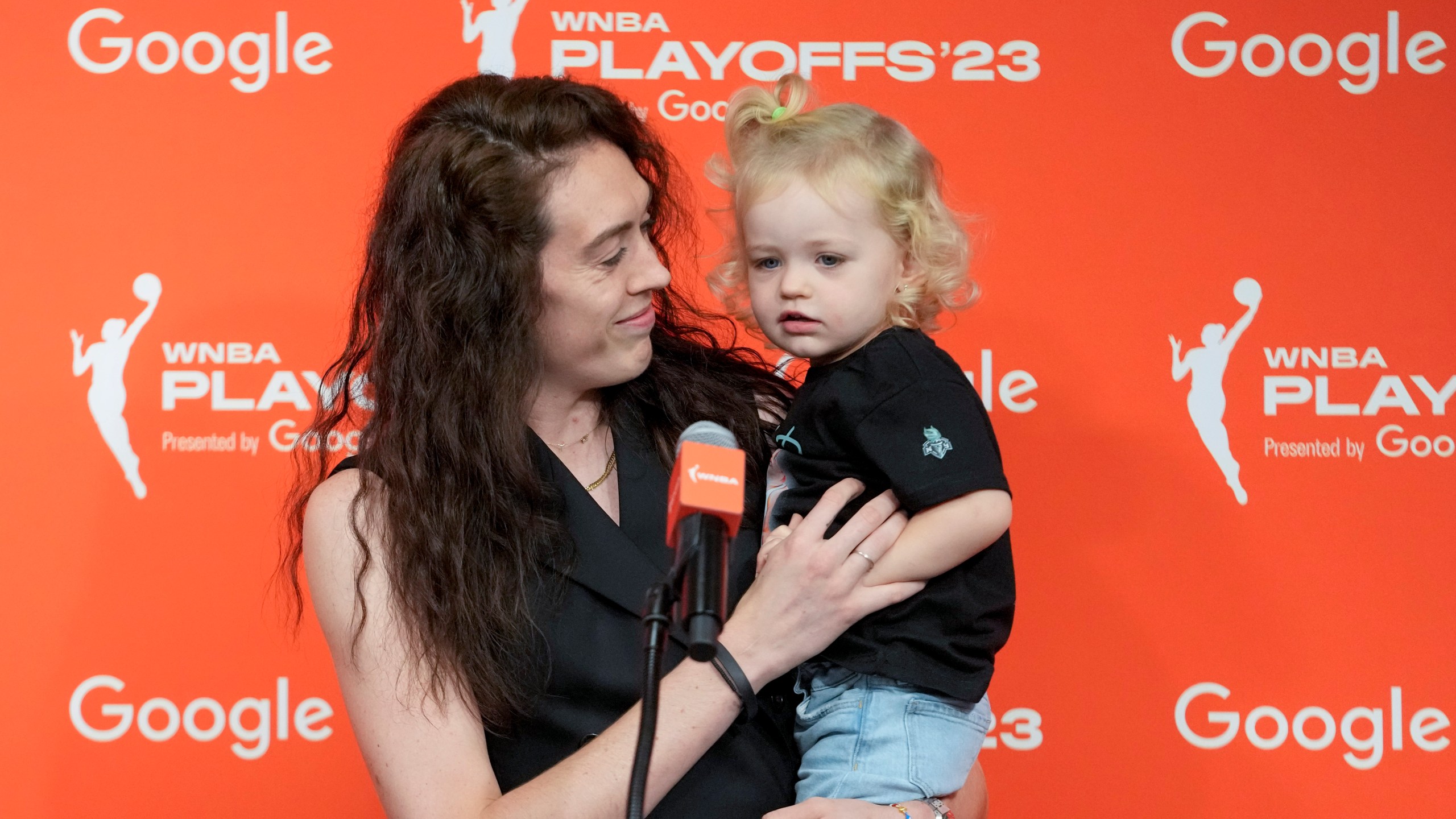 FILE - New York Liberty forward Breanna Stewart holds her daughter Ruby while speaking to reporters, Sept. 26, 2023, at Barclays Center in New York. Stewart, who has two children with wife Marta, appreciates the WNBA's new travel perk of charter flights — as well as other benefits for parents under the current Collective Bargaining Agreement. (AP Photo/Mary Altaffer, File)