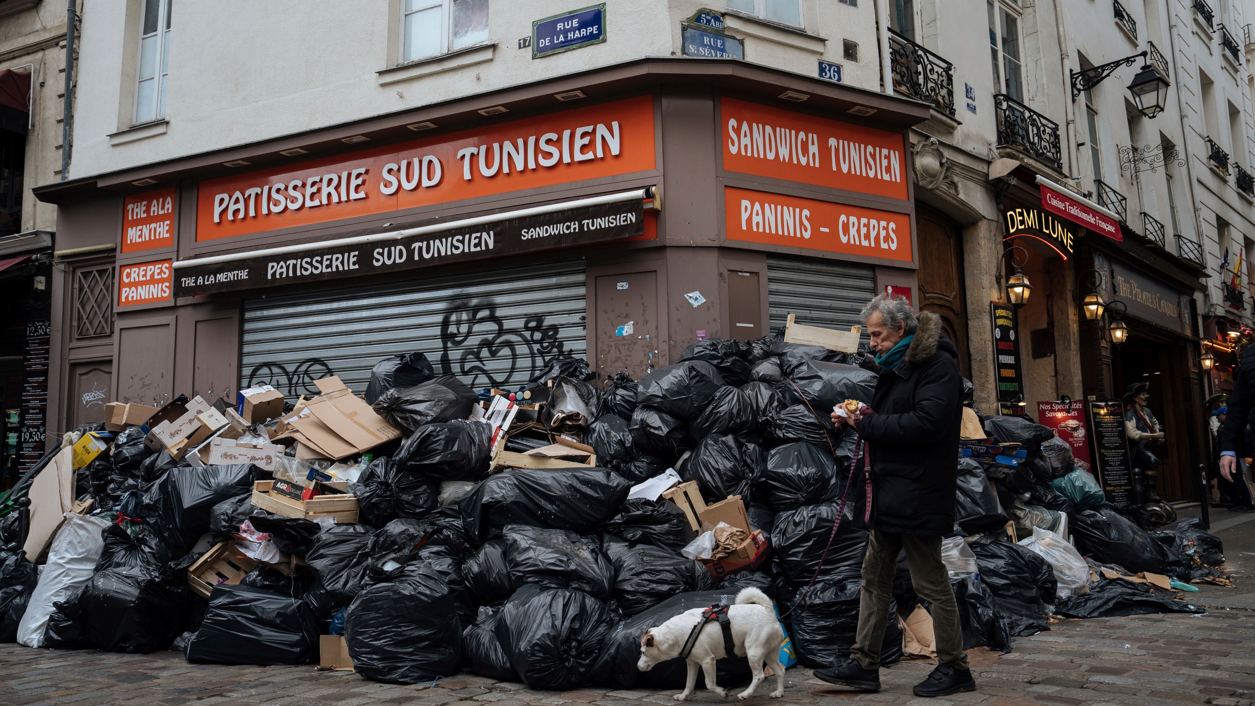 FILE - A man walks past piles of garbage in Paris, on March 13, 2023. Paris garbage collectors have lifted the strike notice that threatened to leave the French capital city under piles of junk during the Olympic Games after striking a deal that will improve their pay. Paris City Hall said in a statement on Wednesday, May 15, 2024 it sealed a deal with the workers and that the strike notice covering several days in May and a period from July to Sept. 8 had been lifted. (AP Photo/Lewis Joly, File)