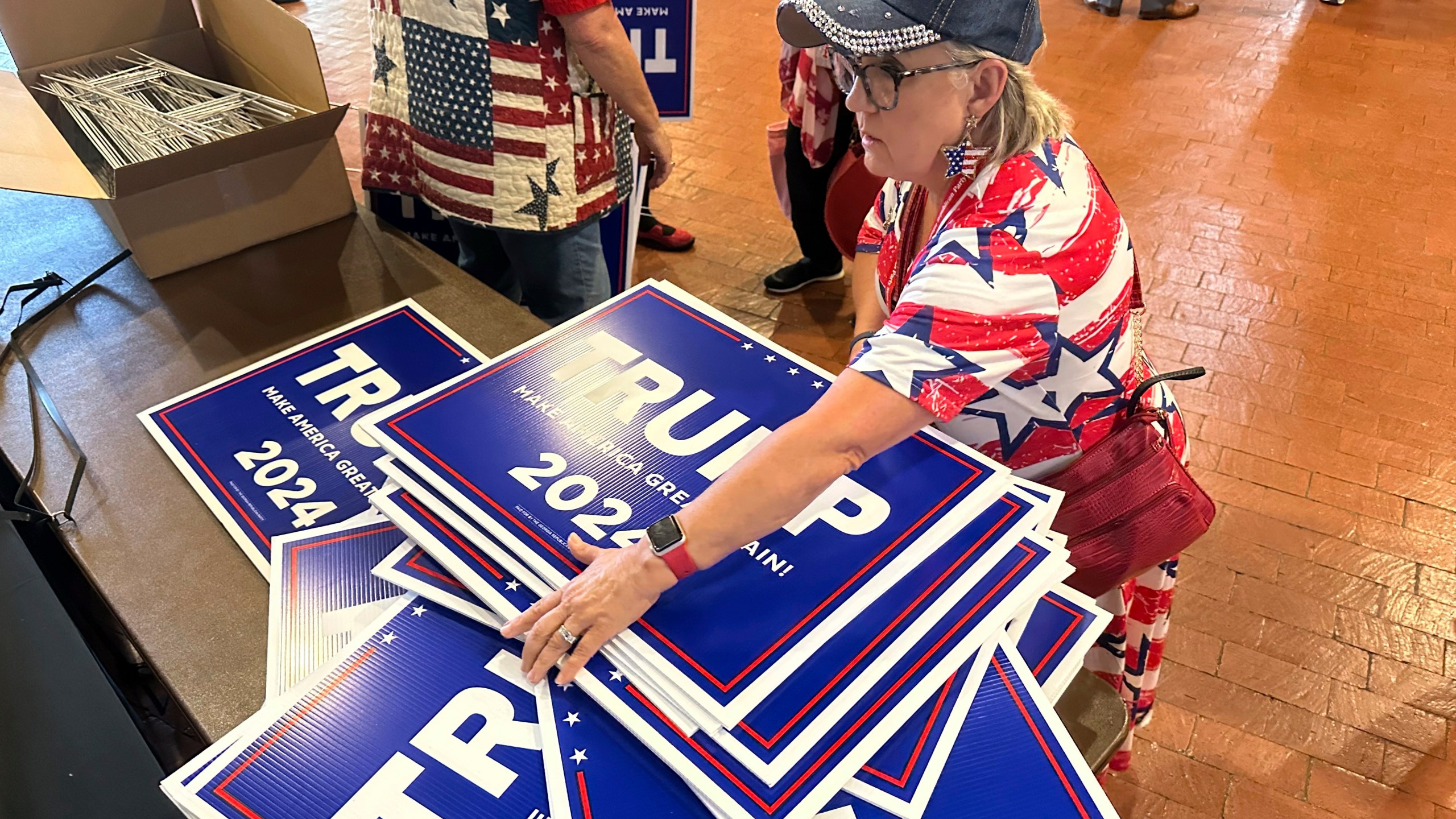 Ginger Hurmence of Lincolnton, Ga., picks up Republican presidential candidate Donald Trump yard signs at the Georgia Republican Party State Convention in Columbus, Ga., on Saturday, May 18, 2024. (AP Photo/Jeff Amy)