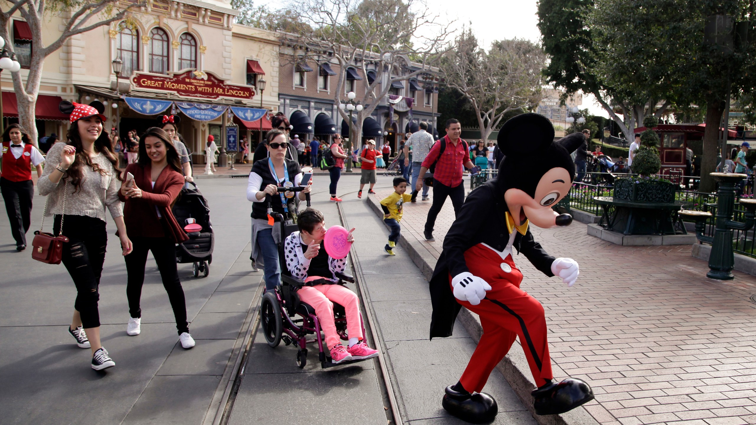 FILE - Visitors follow Mickey Mouse for photos at Disneyland, Jan. 22, 2015, in Anaheim, Calif. Disneyland performers who help bring Mickey Mouse, Cinderella and other beloved characters to life at the Southern California resort chose to unionize following a three-day vote culminating on Saturday, May 18, 2024. (AP Photo/Jae C. Hong, File)