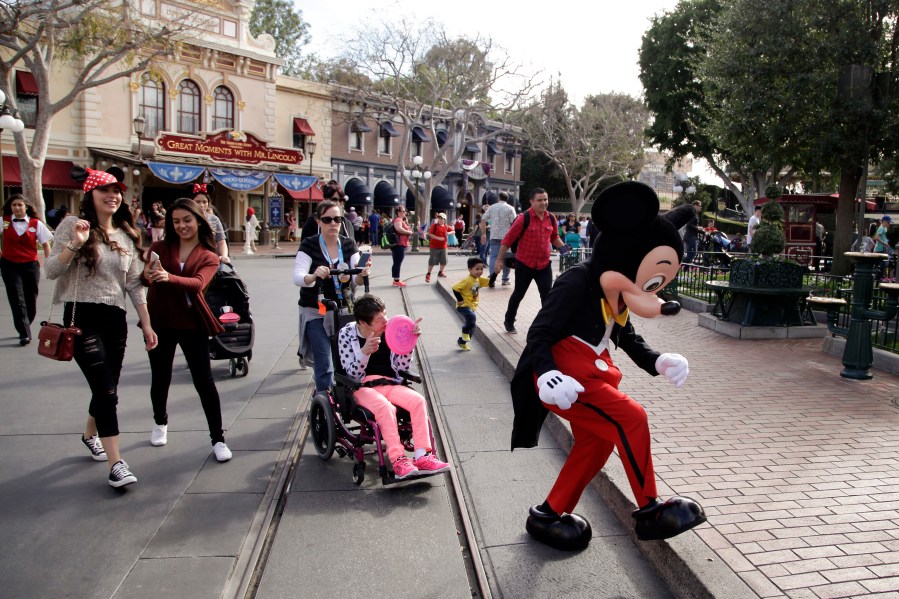 FILE - Visitors follow Mickey Mouse for photos at Disneyland, Jan. 22, 2015, in Anaheim, Calif. Disneyland performers who help bring Mickey Mouse, Cinderella and other beloved characters to life at the Southern California resort chose to unionize following a three-day vote culminating on Saturday, May 18, 2024. (AP Photo/Jae C. Hong, File)