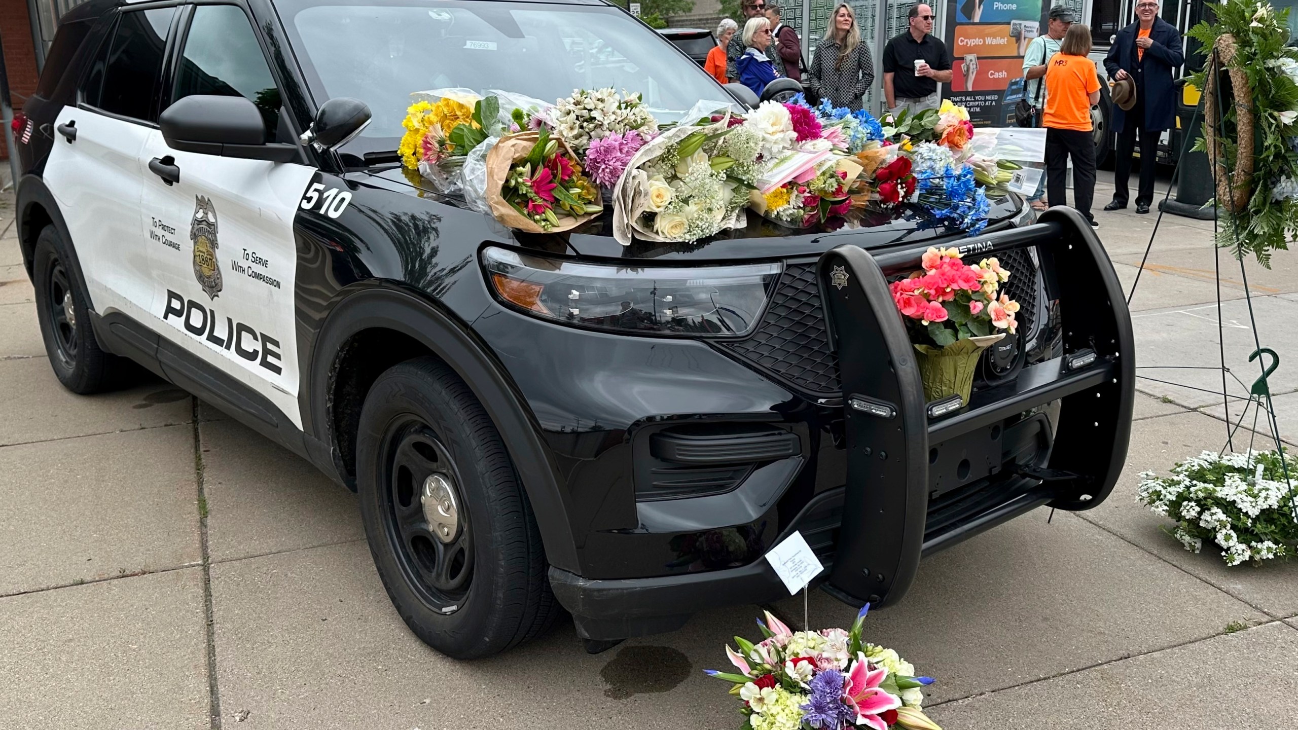 Mourners leave flowers on a police car at a precinct Friday, May 31, 2024, a day after an officer and two others were killed in a shooting. (AP Photo/Mark Vancleave)