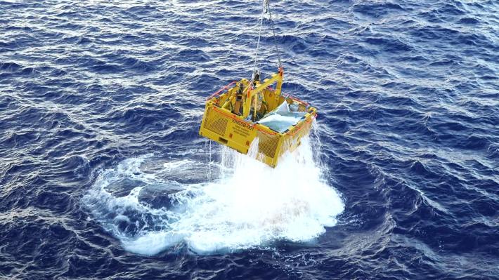 A metal container being hoisted out of the water.