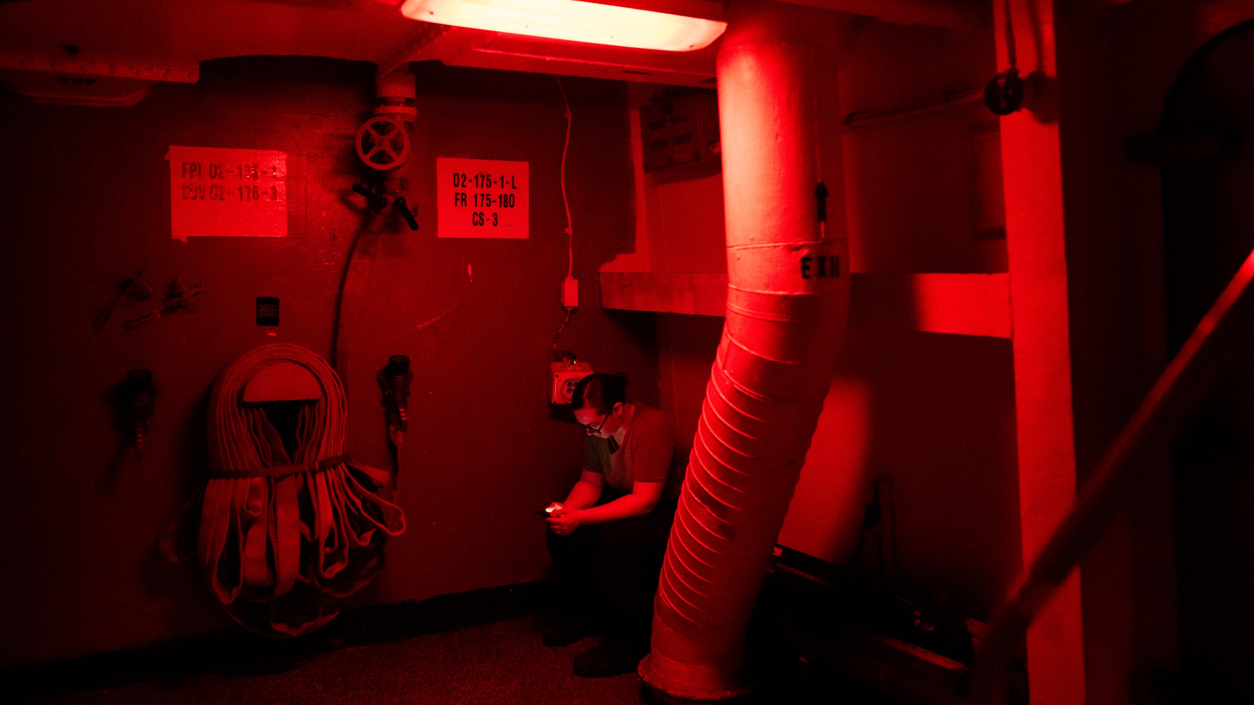 A crew member looks at a cell phone during a break aboard the USS Dwight D. Eisenhower in the Red Sea on Tuesday, June 11, 2024. (AP Photo/Bernat Armangue)