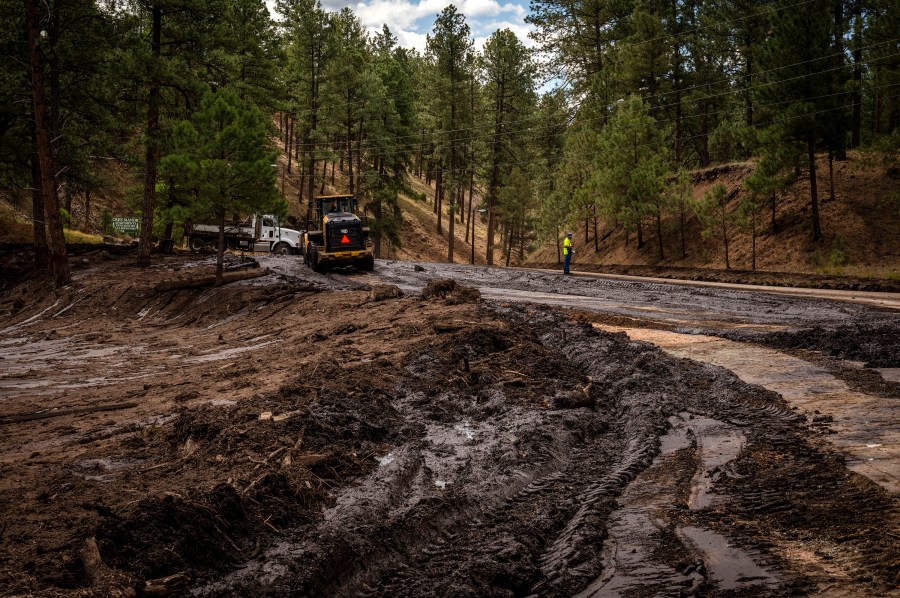 Crews work to remove mud and debris from the aftermath of flooding on Paradise Canyon Drive and Hull Road in Ruidoso, N.M., Monday, June 24, 2024. (Chancey Bush/The Albuquerque Journal via AP)