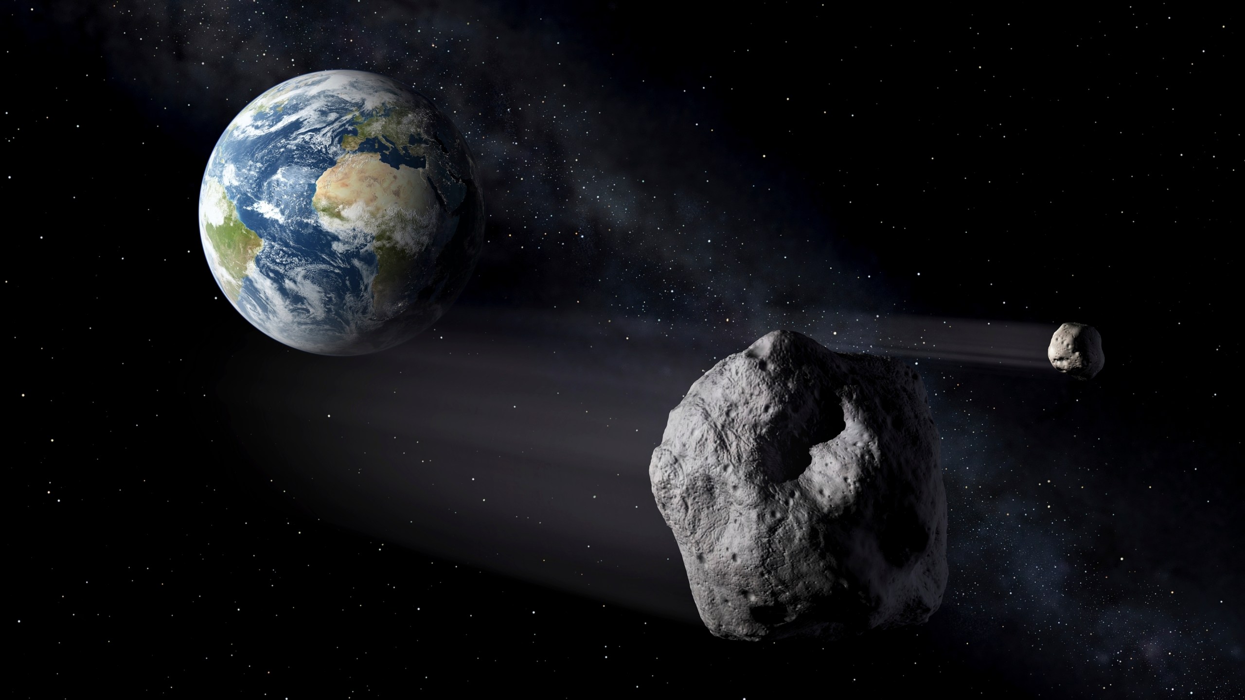 In this artistic rendering, two asteroids fly past Earth. An asteroid will whiz harmlessly past Earth Saturday June 29, 2024. With the right equipment and timing, you just might spot it. Called 2024 MK, the space rock will make its closest approach to Earth at 9:46 AM EST (13:46 GMT) passing by at about three-quarters the distance from Earth to the moon. It was first spotted two weeks ago by South African astronomers and is about 393 feet to 853 feet (120 to 260 meters) wide. (ESA via AP)