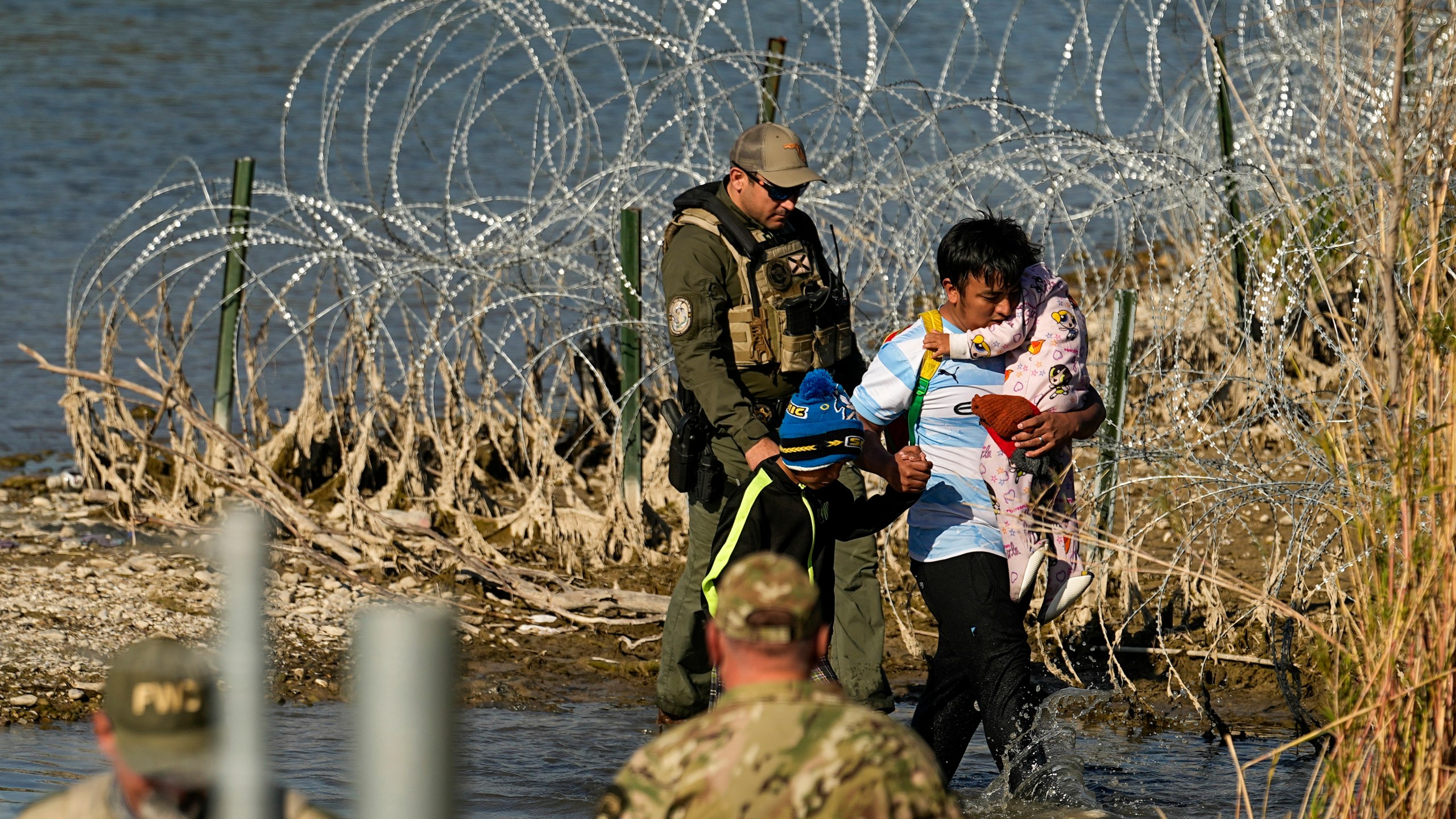 Migrants are taken into custody by officials at the Texas-Mexico border in Eagle Pass, Texas.