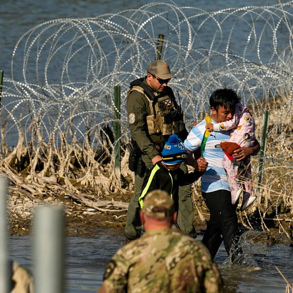 Migrants are taken into custody by officials at the Texas-Mexico border in Eagle Pass, Texas.