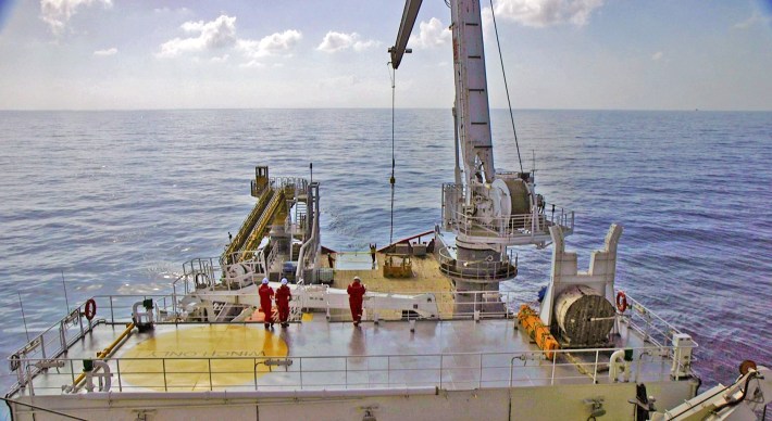 A large basket on a crane attached to a ship.