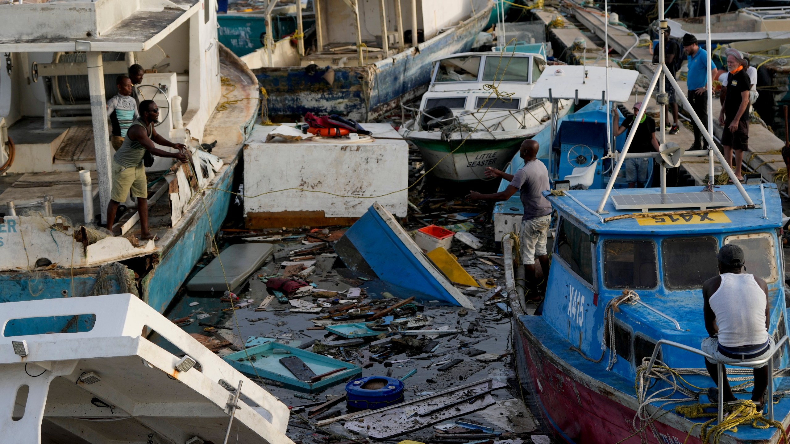 A fisherman throws a rope across boats damaged by Hurricane Beryl at Bridgetown Fisheries, Barbados, Tuesday, July 2, 2024. (AP Photo/Ricardo Mazalan)