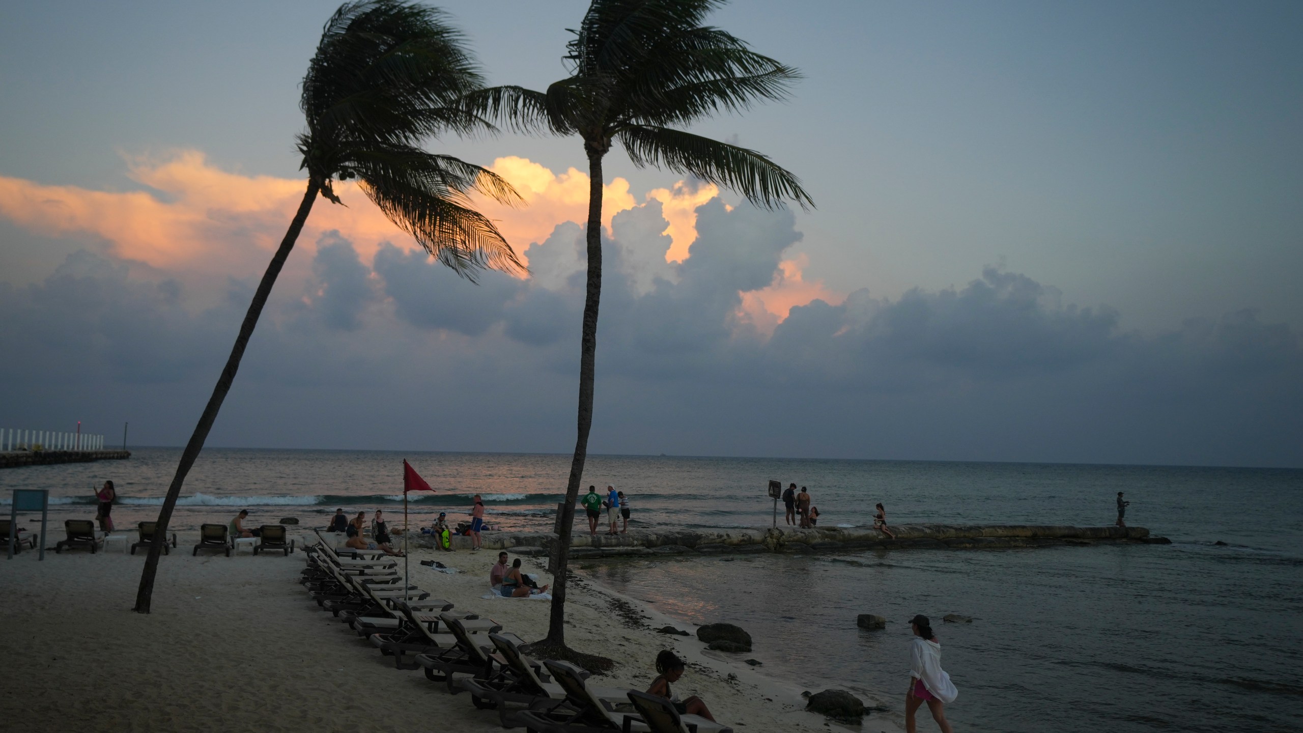 People lounge on the beach as the sun sets ahead of Hurricane Beryl's expected arrival, in Playa del Carmen, Mexico, Wednesday, July 3, 2024. (AP Photo/Fernando Llano)