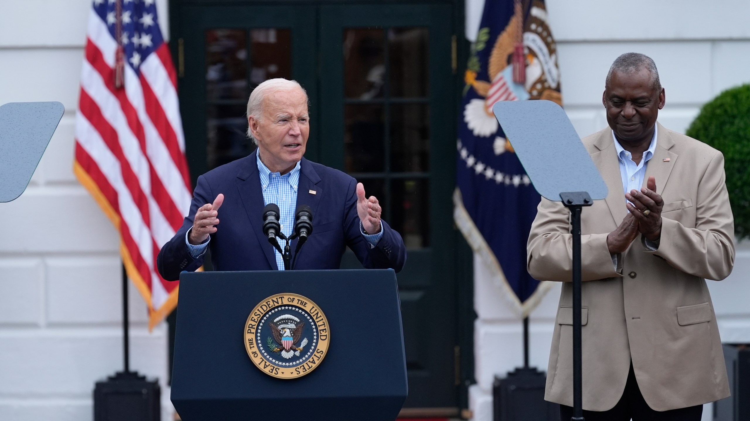 President Joe Biden, left, standing with Defense Secretary Lloyd Austin, right, speaks to active-duty military service members and their families during a Fourth of July celebration and barbecue on the South Lawn of the White House in Washington, Thursday, July 4, 2024. (AP Photo/Susan Walsh)