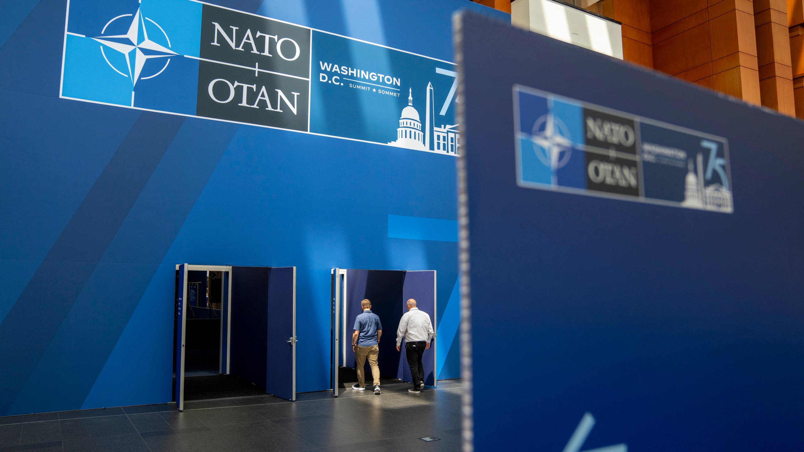 People walk inside of the Walter E. Washington Convention Center, which has been decorated with signage in preparation for the NATO Summit, Monday, July 8, 2024. New Zealand, Japan, South Korea and Australia are sending leaders or their deputies to the NATO summit in Washington this week as the military alliance shows growing interest beyond Europe and the Western Hemisphere. (AP Photo/Jacquelyn Martin)