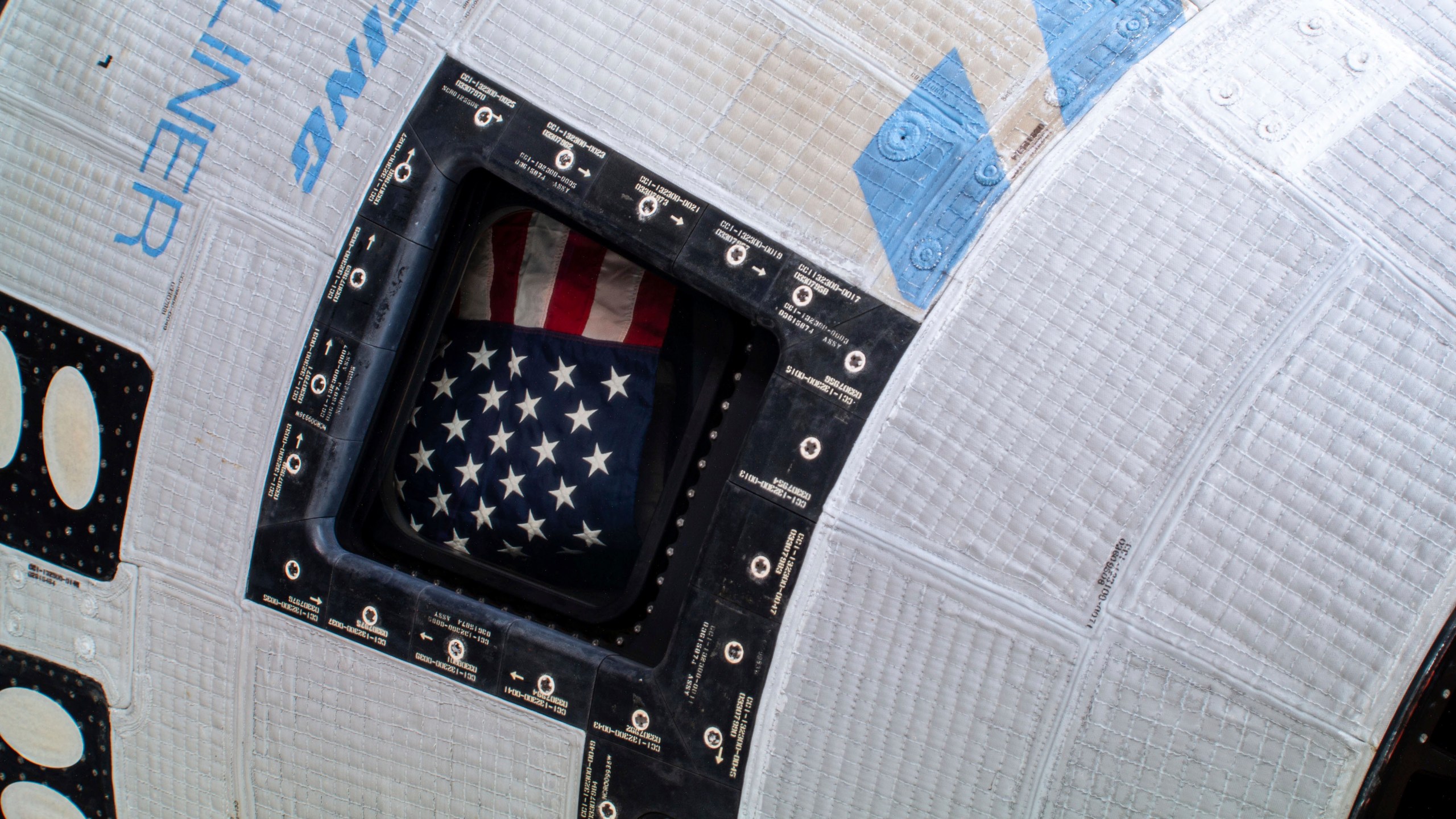 In this photo provided by NASA, a U.S. flag is displayed from a window of the Boeing Starliner spacecraft docked to the International Space Station on Tuesday, July 2, 2024. (NASA via AP)