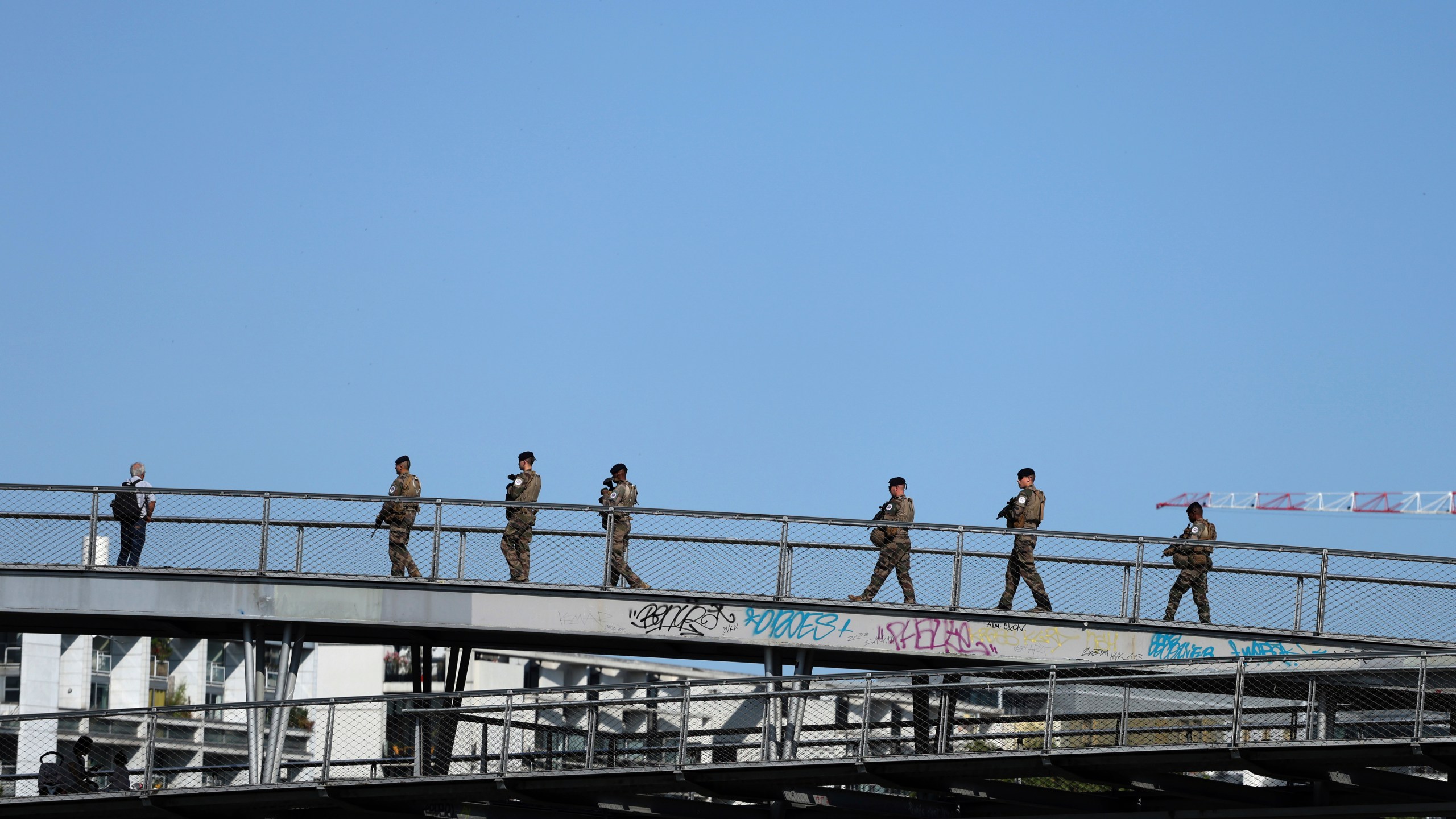 Soldiers patrol on a footbridge over the Seine river, Wednesday, July 17, 2024 in Paris. France's armed forces held a demonstration of the security measures planned on the River Seine, both in and out of the water, to make it safe for athletes and spectators during the opening ceremony of the Paris Olympics. Organizers have planned a parade of about 10,000 athletes through the heart of the French capital on boats on the Seine along a 6-kilometer (3.7-mile) route at sunset on July 26. (AP Photo/Aurelien Morissard)