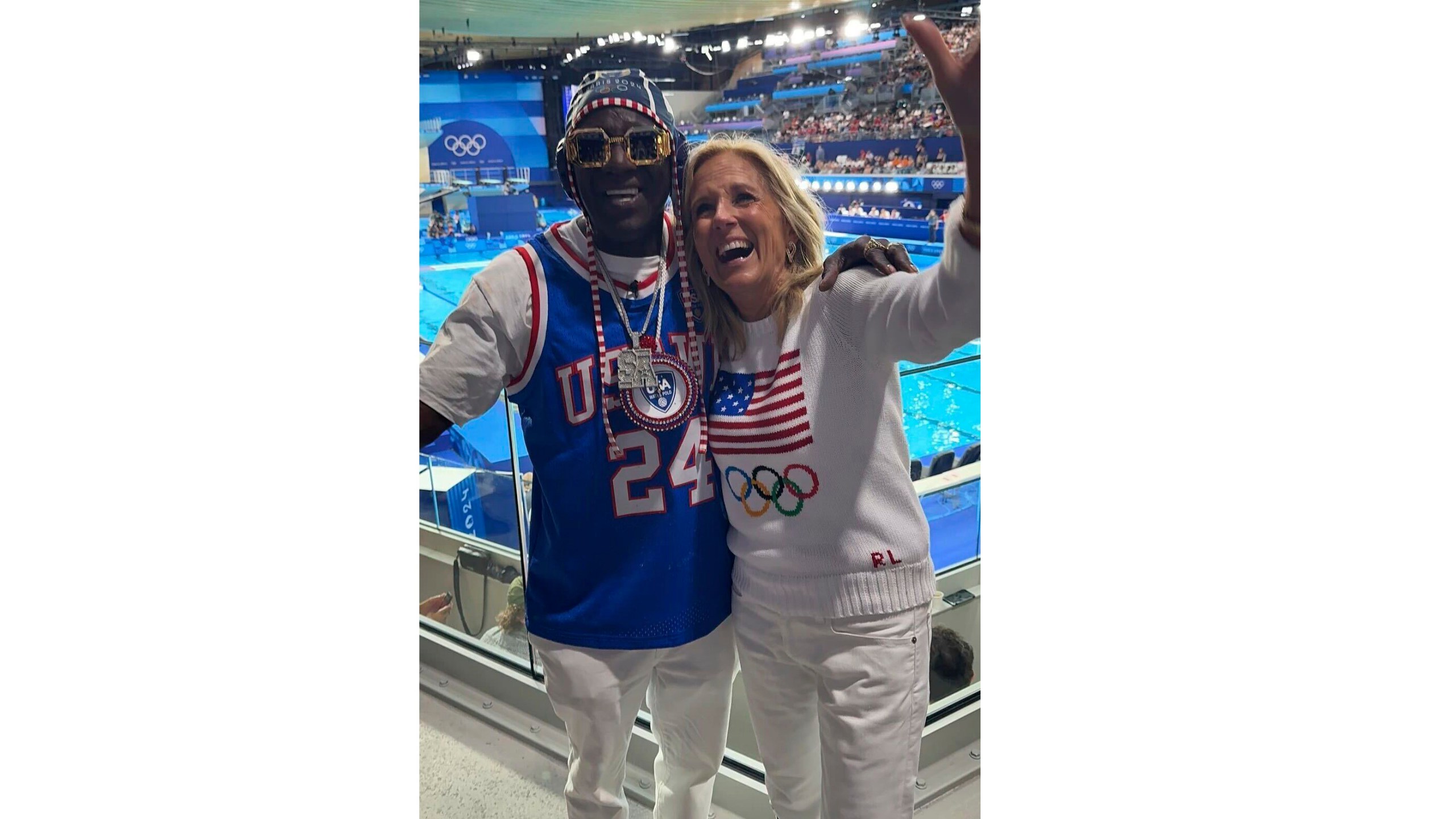 In this photo provided by Rhiannon Rae Ellis on Saturday, July 27, 2024, U.S. First Lady Jill Biden poses for a photo with Flavor Flav during a women's Water Polo match, at the 2024 Summer Olympics, Saturday, July 27, 2024, in Saint-Denis, France. (Rhiannon Rae Ellis via AP)