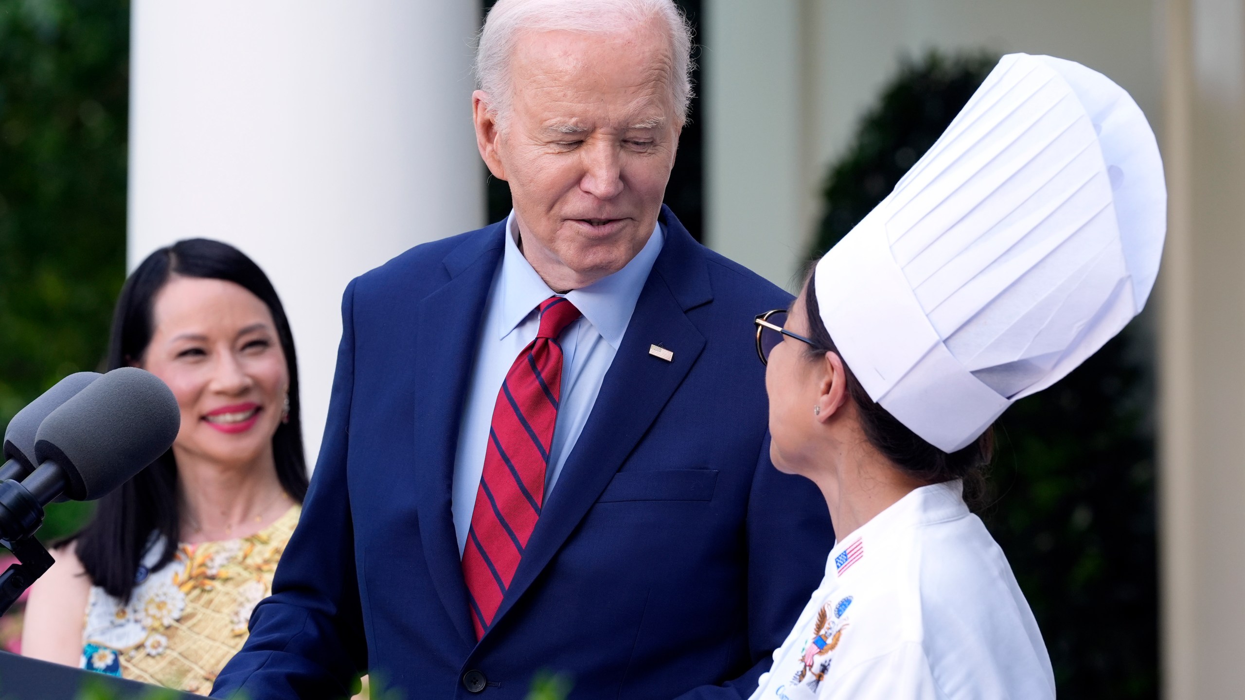 FILE - President Joe Biden looks toward White House Executive Chef Cris Comerford as actor Lucy Liu watches in the Rose Garden of the White House in Washington, May 13, 2024, during a reception celebrating Asian American, Native Hawaiian, and Pacific Islander Heritage Month. Comerford has retired after nearly three decades of making meals and cooking up state dinners for five different presidents and their families. (AP Photo/Susan Walsh, File)