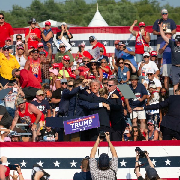 Donald Trump is seen with blood on his face surrounded by secret service agents as he is taken off the stage at a campaign event in Butler, Pennsylvania