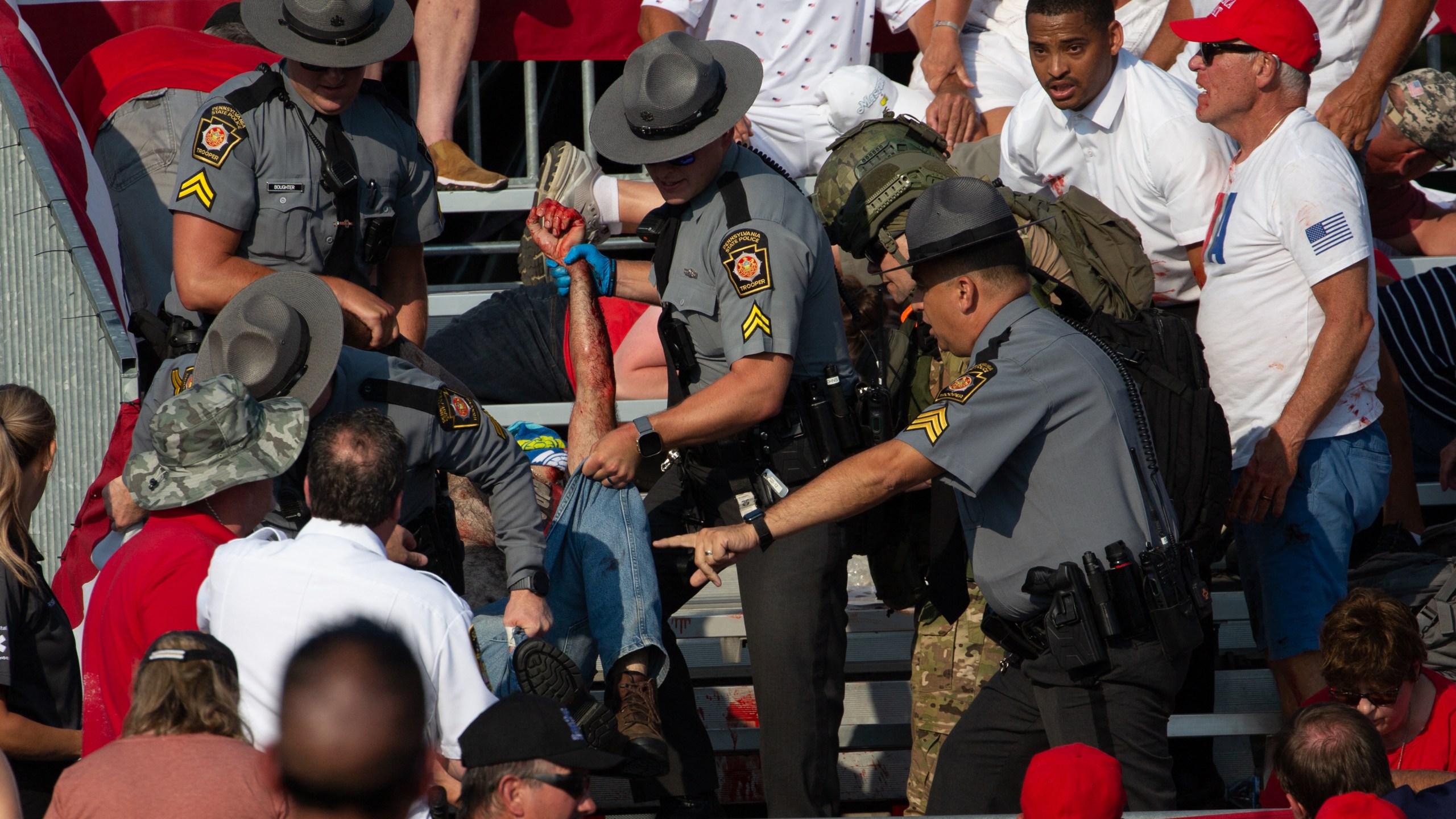 A person is removed by state police from the stands after guns were fired at Republican candidate Donald Trump.