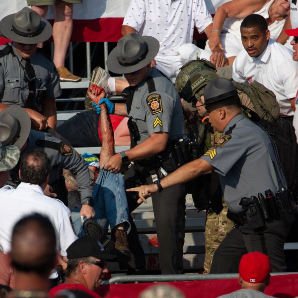 A person is removed by state police from the stands after guns were fired at Republican candidate Donald Trump.