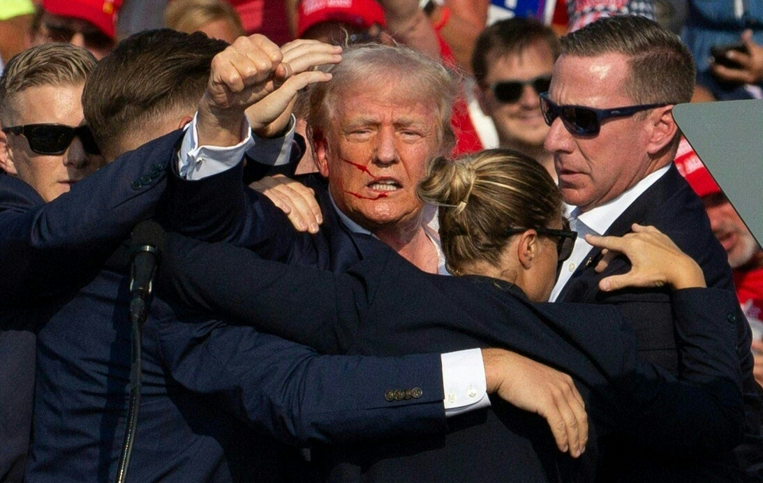 Donald Trump is seen with blood on his face surrounded by Secret Service agents on Saturday