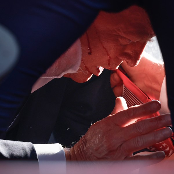 An injured Donald Trump on the ground shielded by Secret Service.