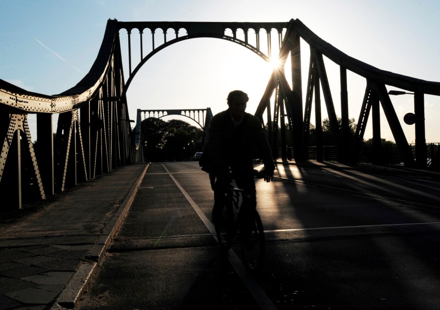 FILE - A cyclist passes over the Glienicke Bridge between Potsdam and Berlin, Germany, on May 6, 2009. They sometimes see those who are part of the swap as they pass each other on an airport tarmac or, as in the Cold War, the Glienicke Bridge connecting West Berlin to Potsdam. In decades of prisoner exchanges, those released have included spies, journalists, drug and arms dealers, and even a well-known athlete. (AP Photo/Sven Kaestner, File)