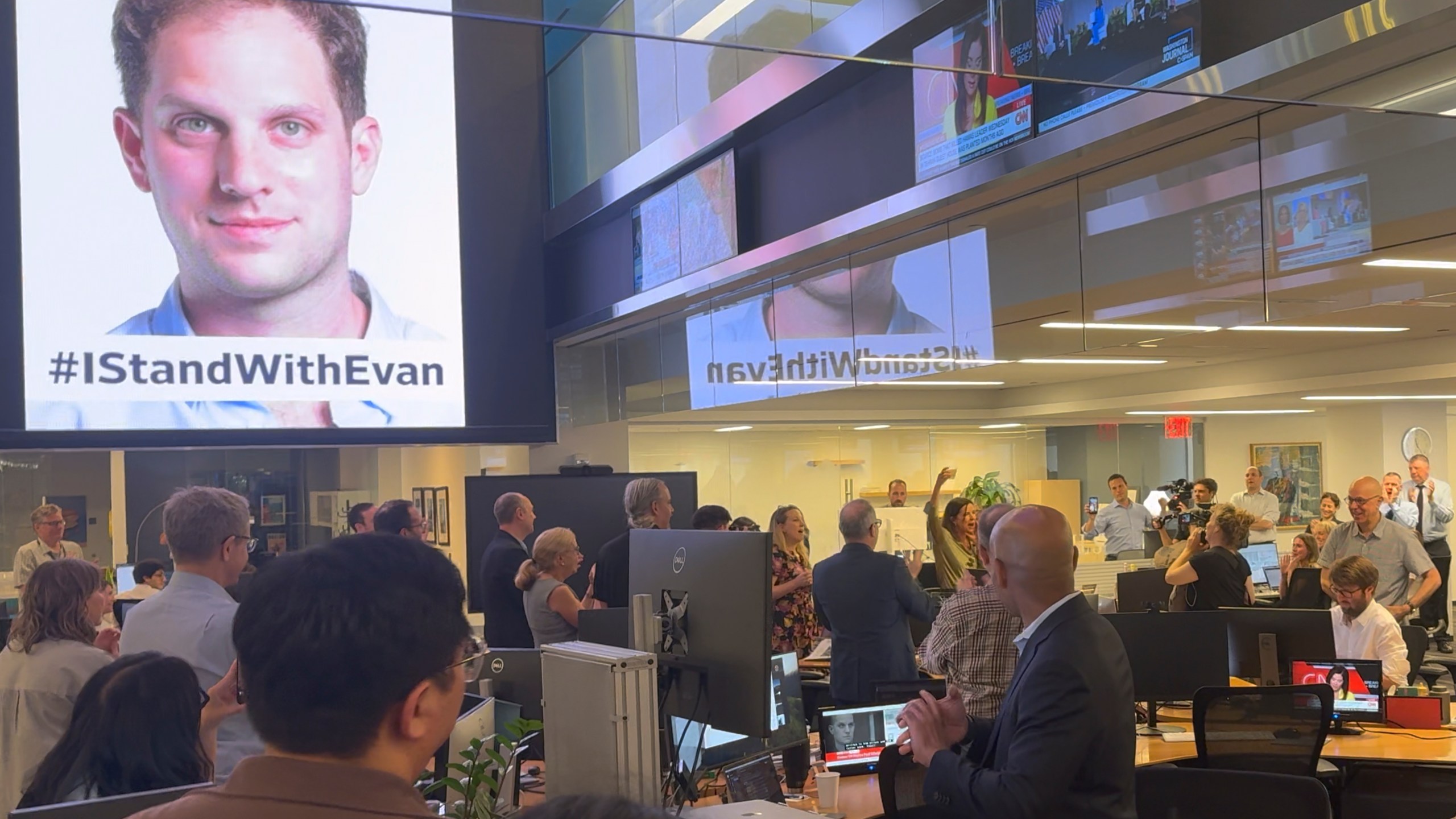 In this image taken from video, employees at the Wall Street Journal in New York applaud at the news that reporter Evan Gershkovich, pictured top left, has been released as part of a prisoner swap with Russia, the United States and several other countries, Thursday, Aug. 1, 2024. (Vaughn Sterling/The Wall Street Journal via AP)