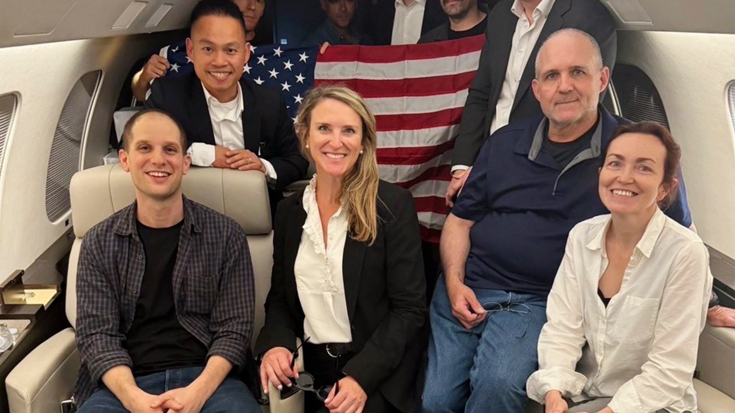 This image released by the White House shows Evan Gershkovich, left, Alsu Kurmasheva, right, and Paul Whelan, second from right, and others aboard a plane, Thursday, Aug. 1, 2024, following their release from Russian captivity. (White House via AP)