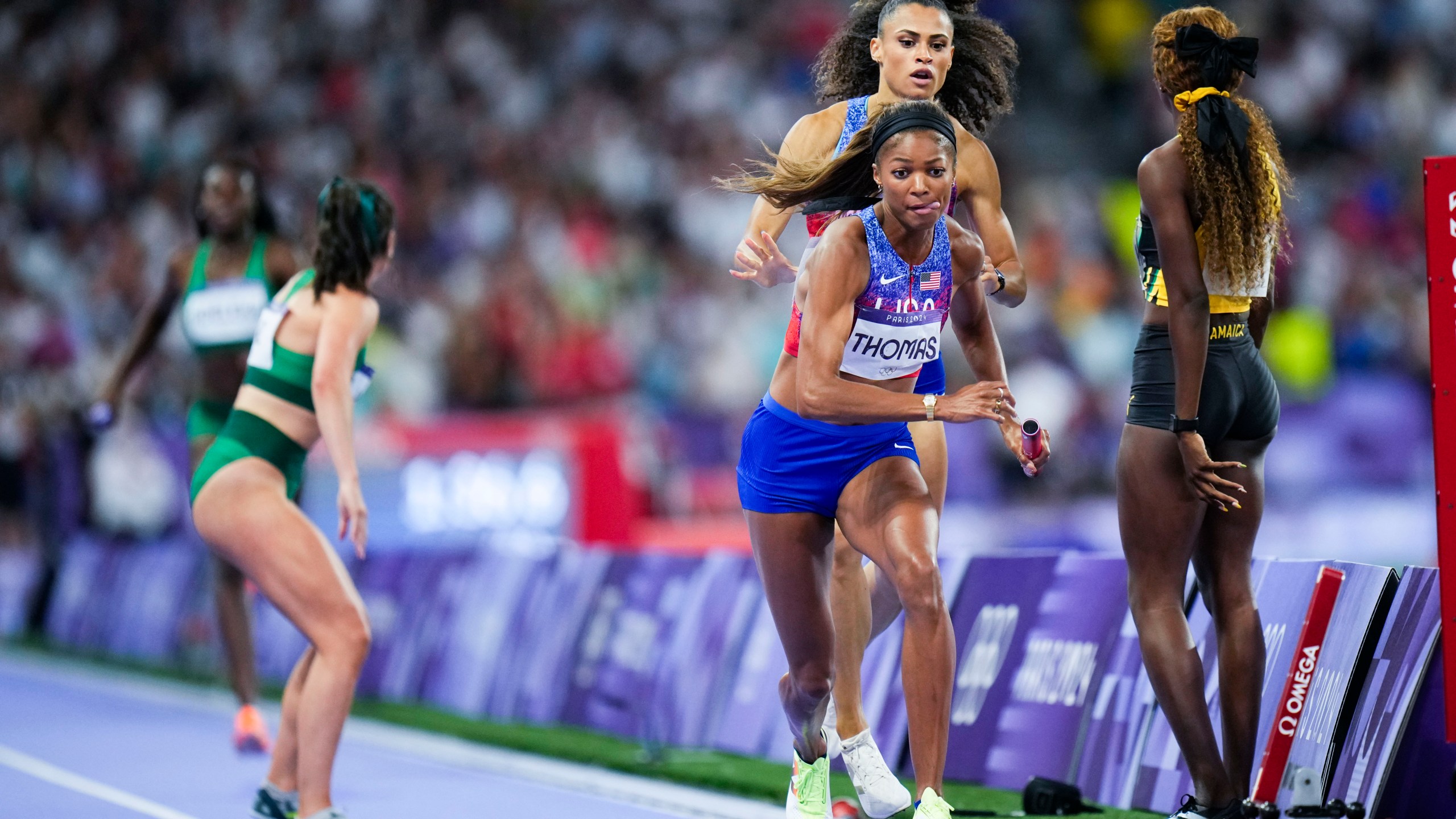 Sydney McLaughlin-Levrone hands off to Gabrielle Thomas, of the United States, during the women's 4 x 400-meter relay final at the 2024 Summer Olympics, Saturday, Aug. 10, 2024, in Saint-Denis, France. (AP Photo/Petr David Josek)