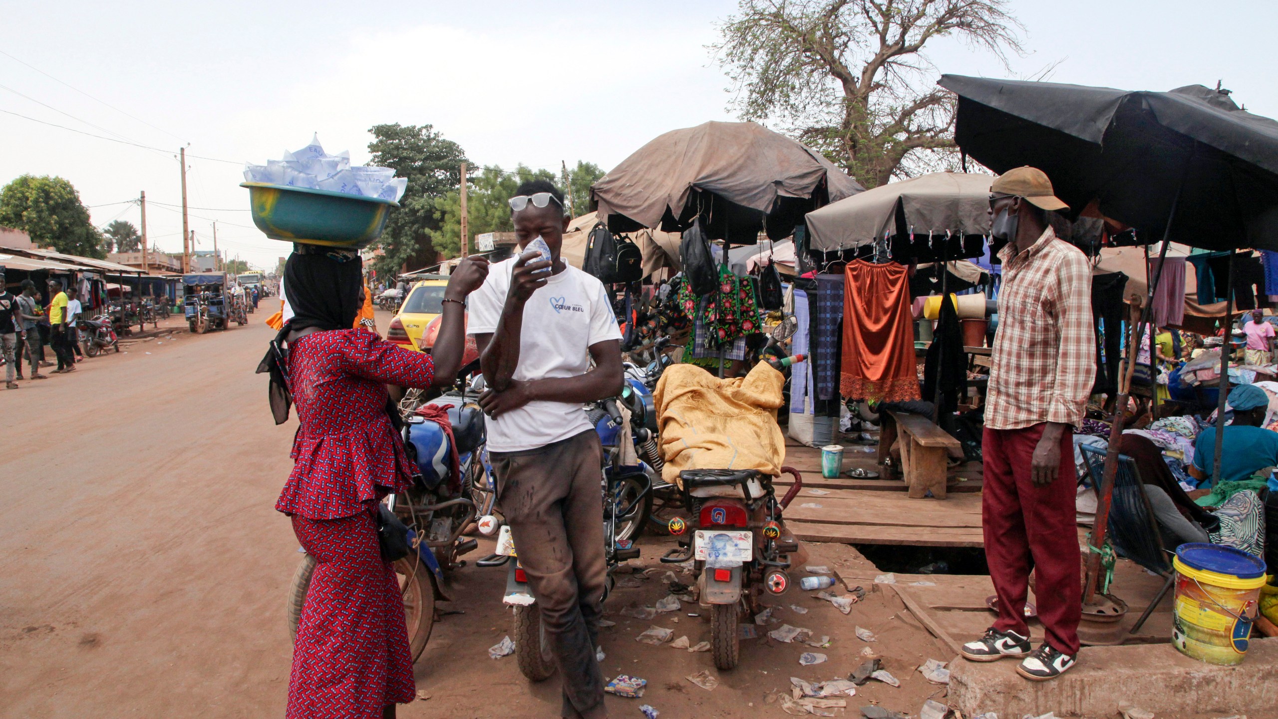 FILE - Amadou Coulibaly, a motorcycle taxi driver, drinks a sachet water to cool off under a blazing sun in Bamako, Mali, on April, 18, 2024. (AP Photo/Baba Ahmed, File)